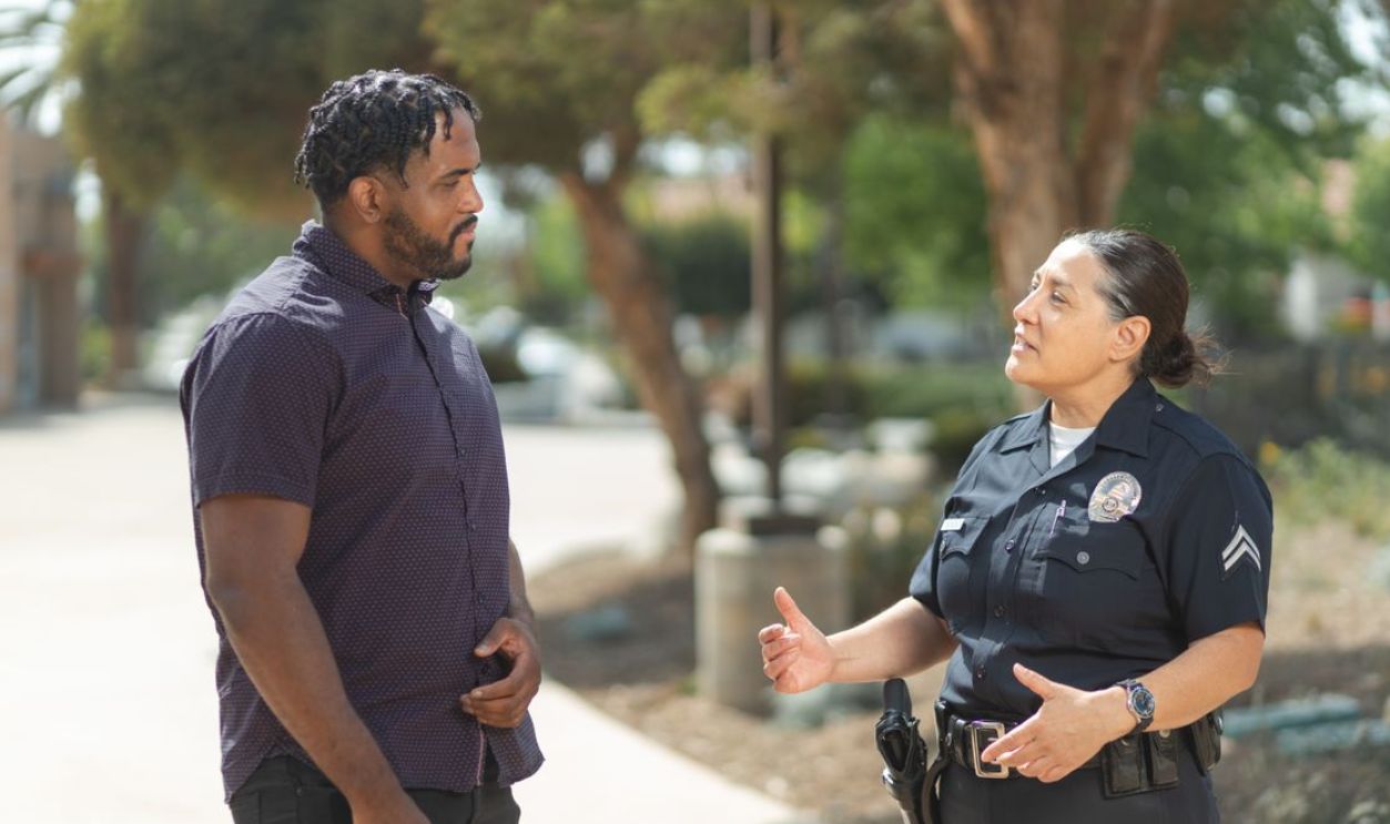 A police officer engaging warmly with a community member outdoors on a sunny day