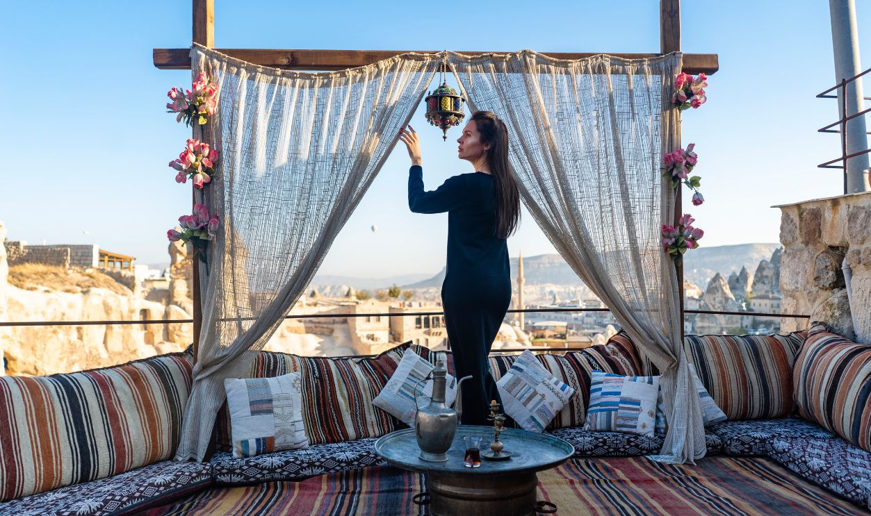 A woman arranges a lantern on a traditional Turkish terrace in Cappadocia, showcasing unique decor