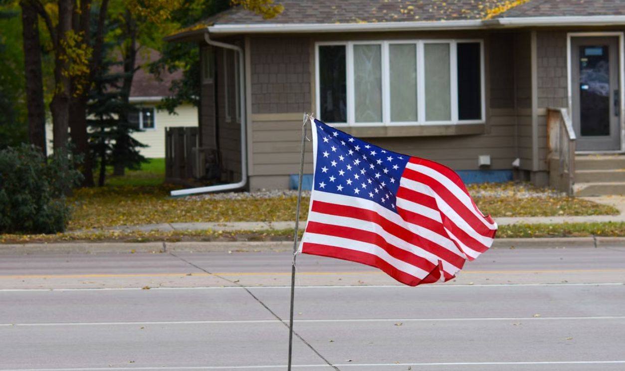 Vibrant American flag waving in a quiet suburban neighborhood during fall