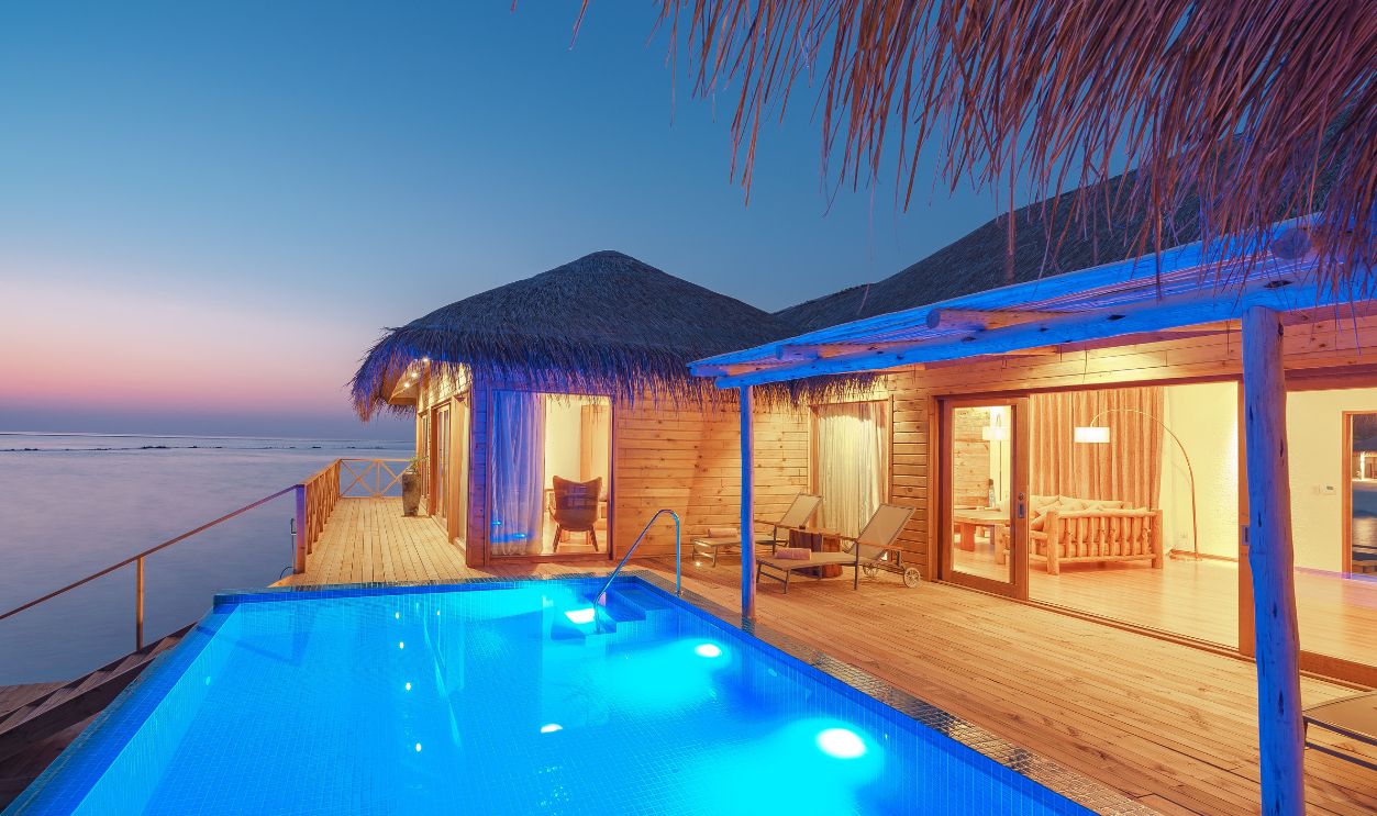 Tranquil overwater bungalow with infinity pool and ocean view at sunset. Perfect tropical paradise getaway