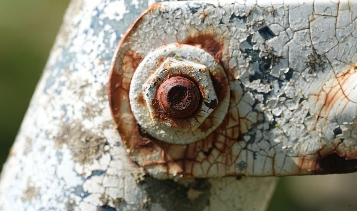 Detailed macro shot of a rusty bolt on cracked, weathered metal showcasing texture