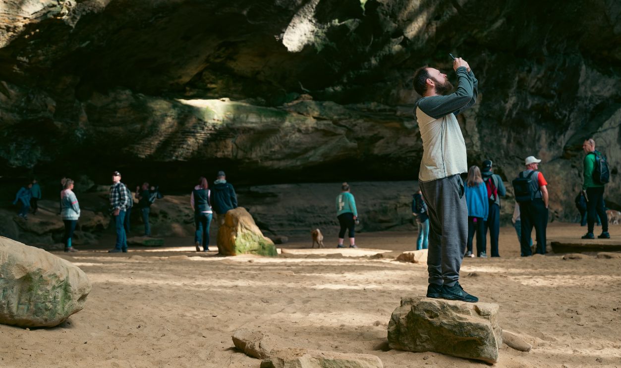 A tourist takes a photo inside a stunning cave with rock formations and visitors
