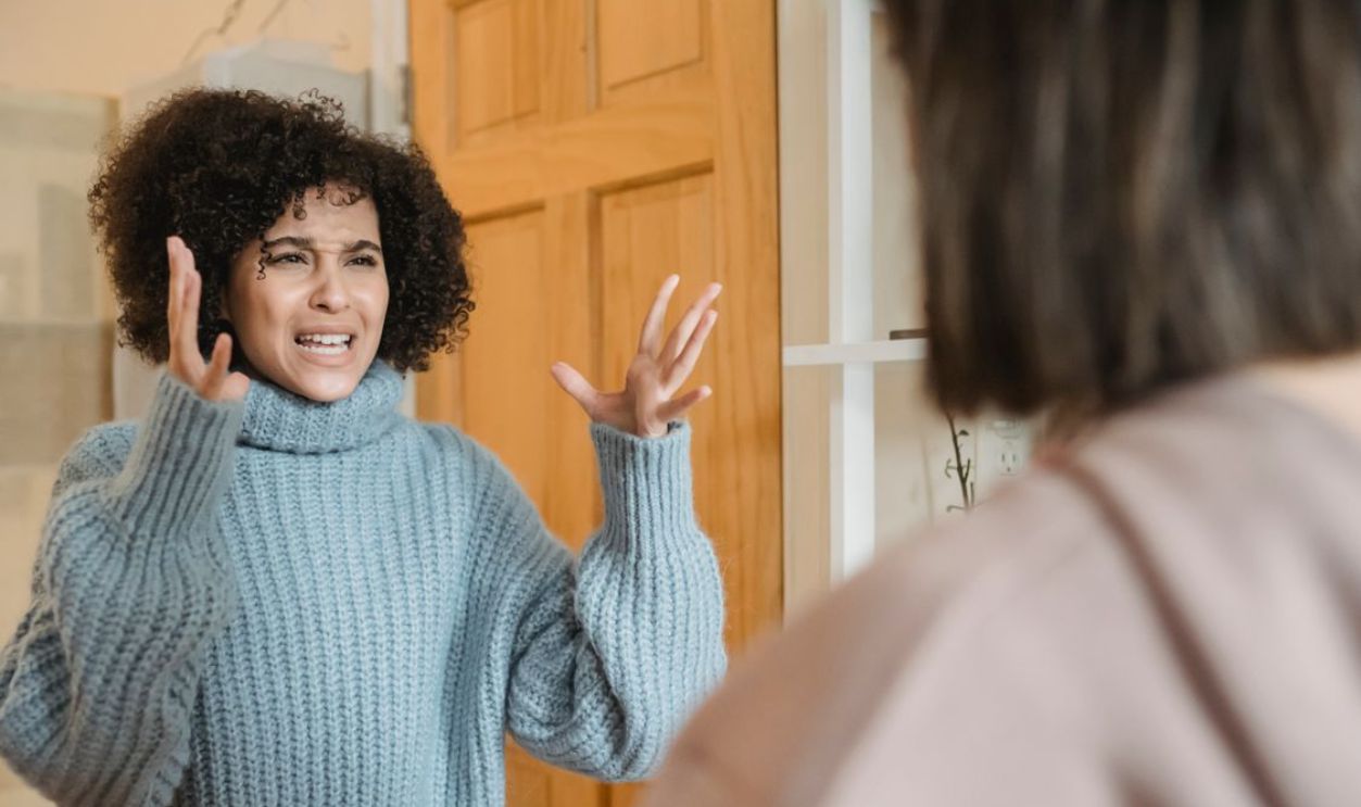 Two women engaged in an expressive and intense conversation indoors, showcasing strong emotions.