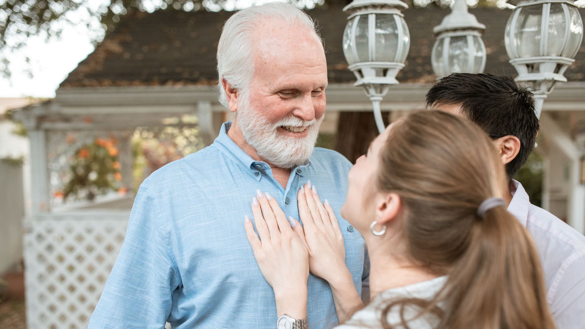 A joyful moment shared between a grandfather and his family outdoors on a sunny day.