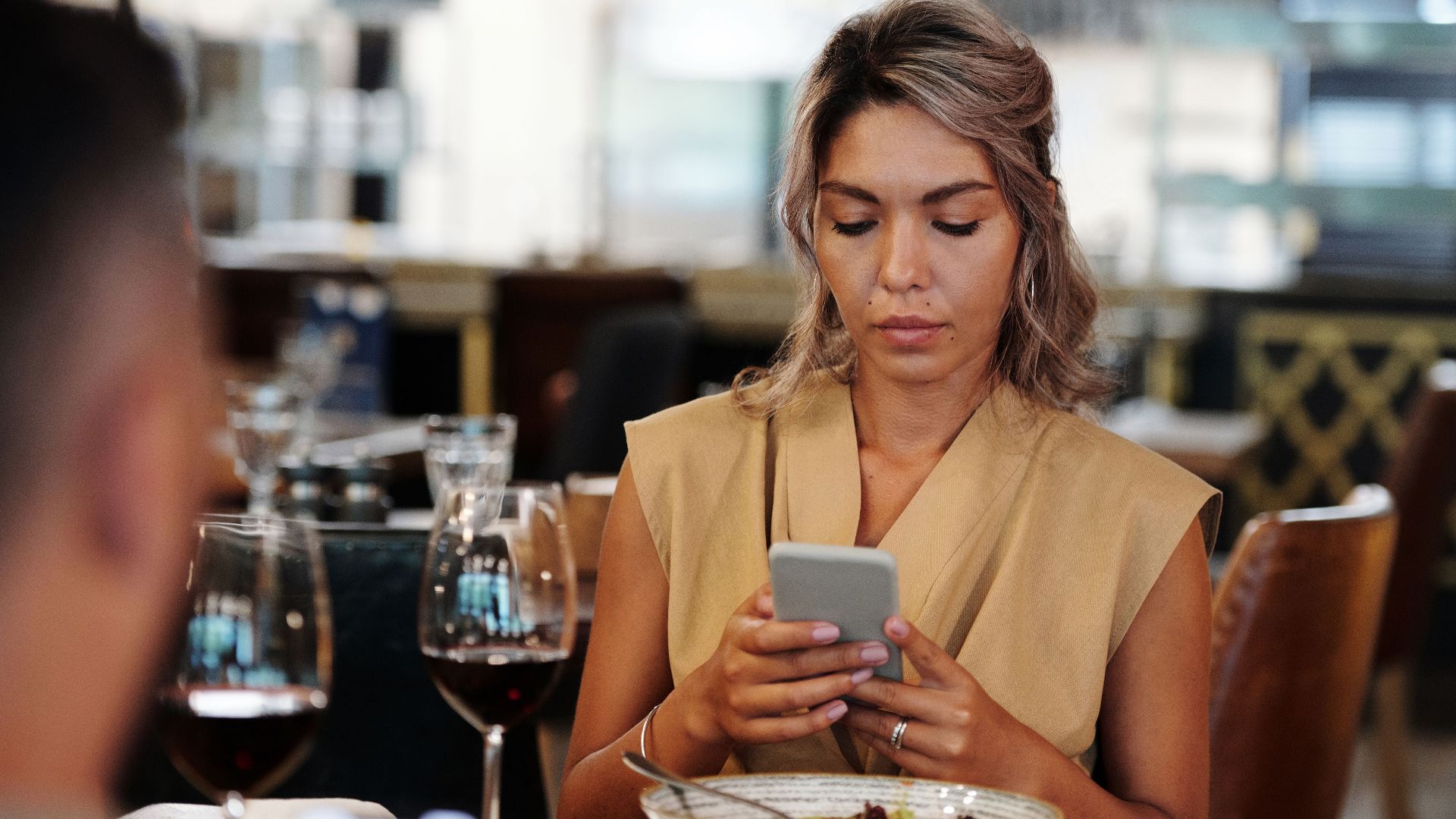 A woman focused on her smartphone while dining in a restaurant.