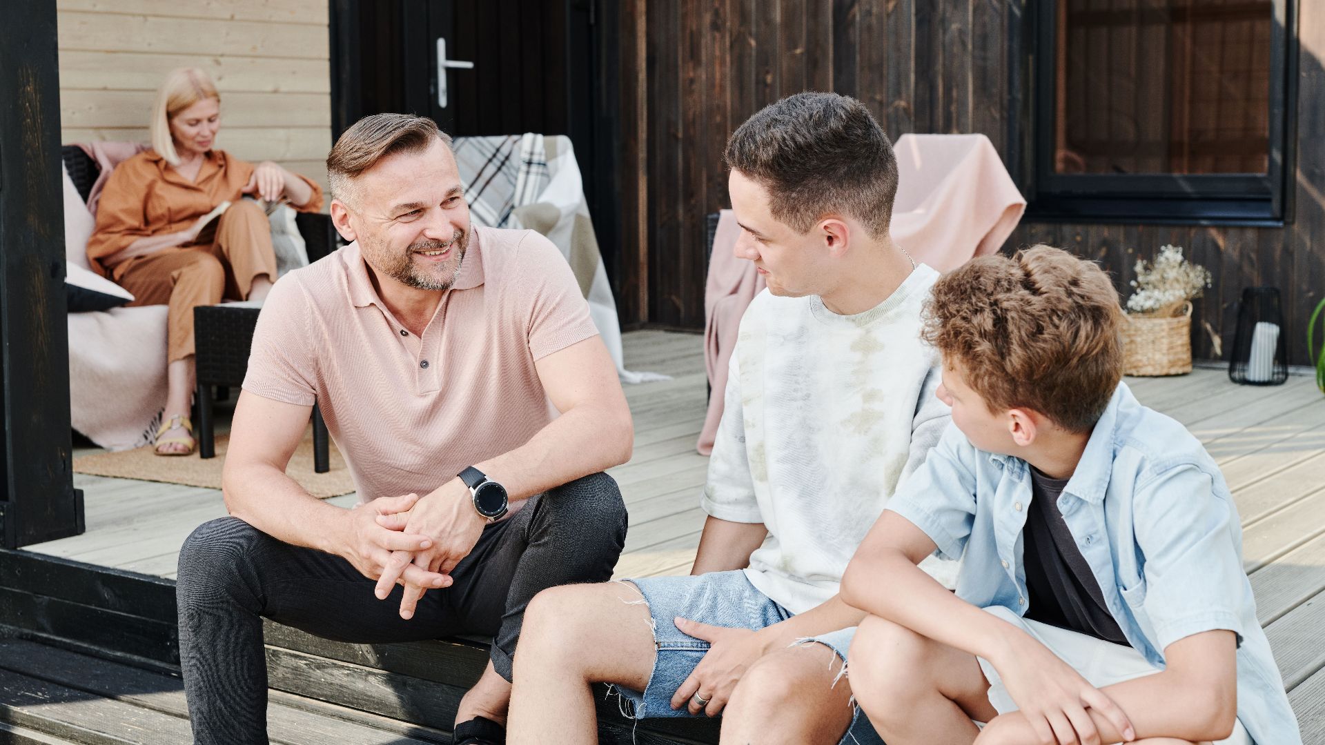 Family sharing quality time on a wooden terrace. Smiling and conversing.