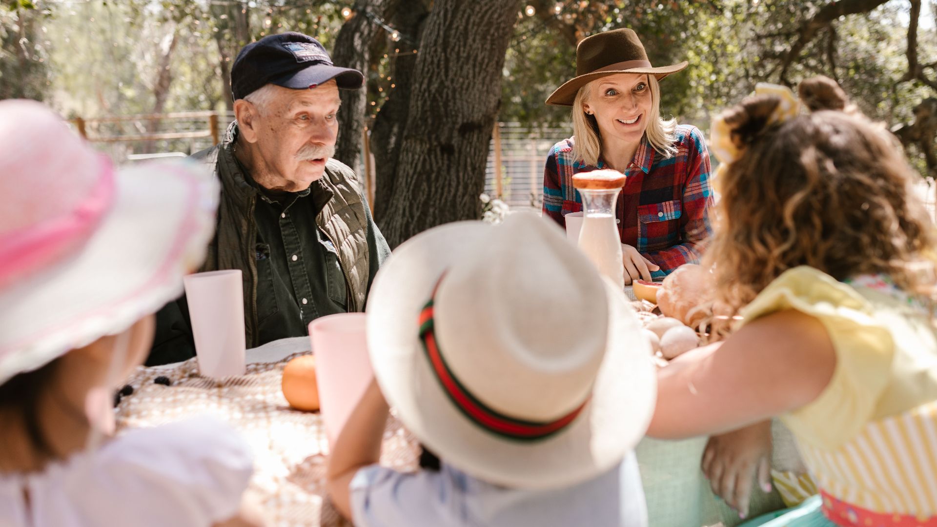 A joyful family picnic with adults and children enjoying a sunny day outdoors.