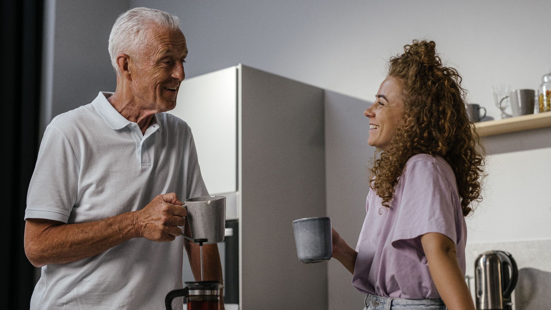 A joyful moment of a grandfather and granddaughter enjoying coffee in a modern kitchen.