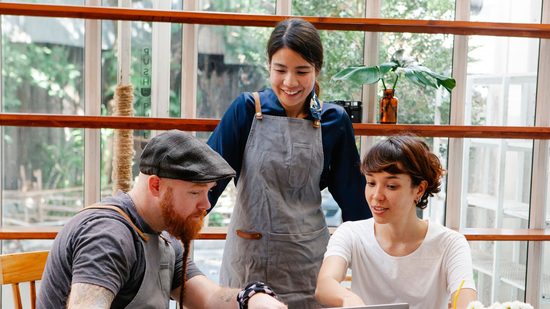 Smiling young multiracial coworkers with coffee using netbook while speaking at table in cafe