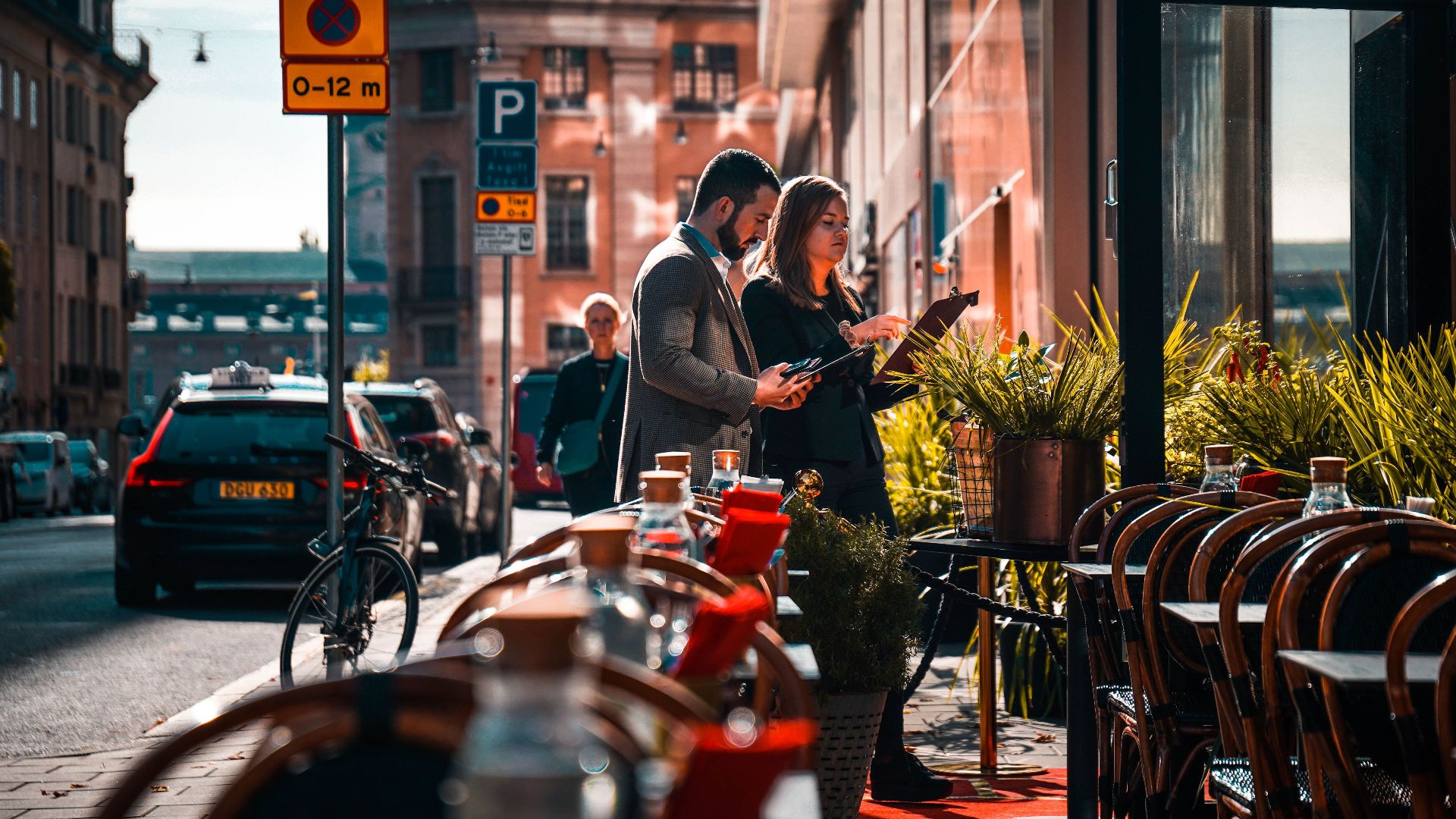 Professionals standing outside a street cafe reviewing documents. Urban cityscape during daylight.