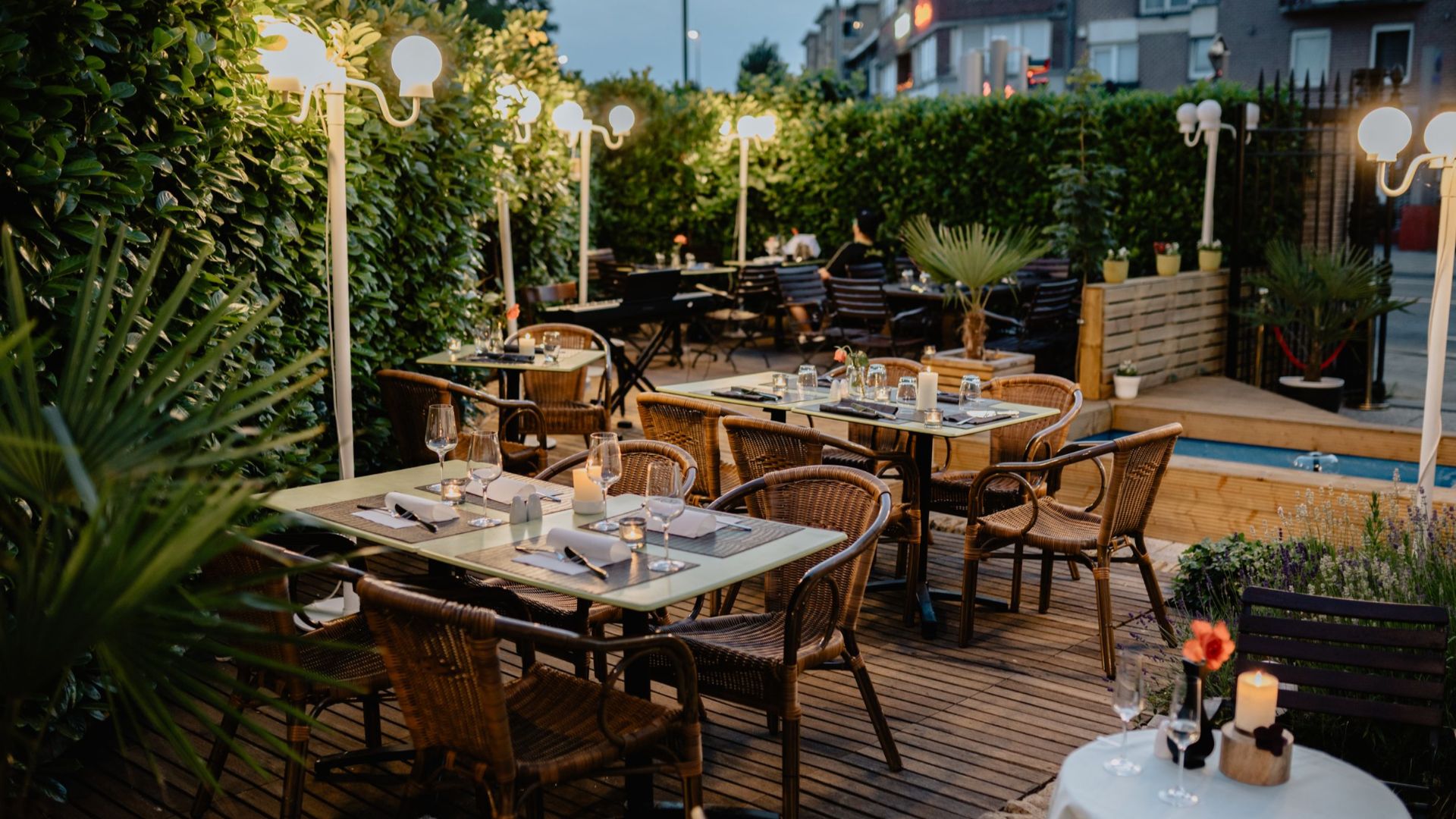 Cozy outdoor restaurant terrace with wicker chairs, tables, and warm lighting for evening dining.