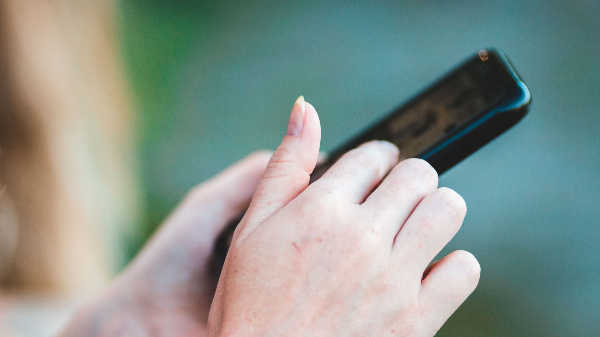 Hands holding a smartphone with blurred background, showcasing modern technology use.