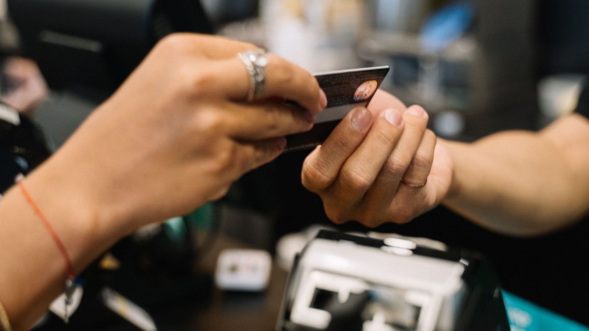 Close-up of hands completing a payment transaction at a retail checkout using a bank card.