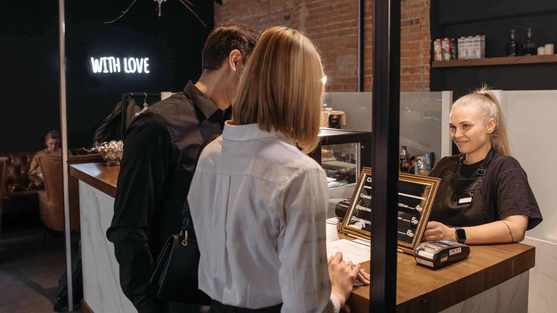 A warm interaction at a café counter featuring a smiling barista and customers.