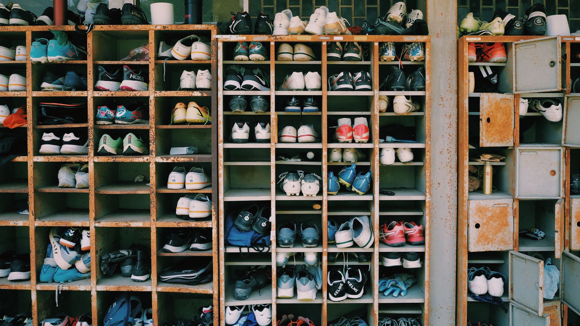 Rusted shelves filled with various shoes in a public storage area in Tokyo, Japan.