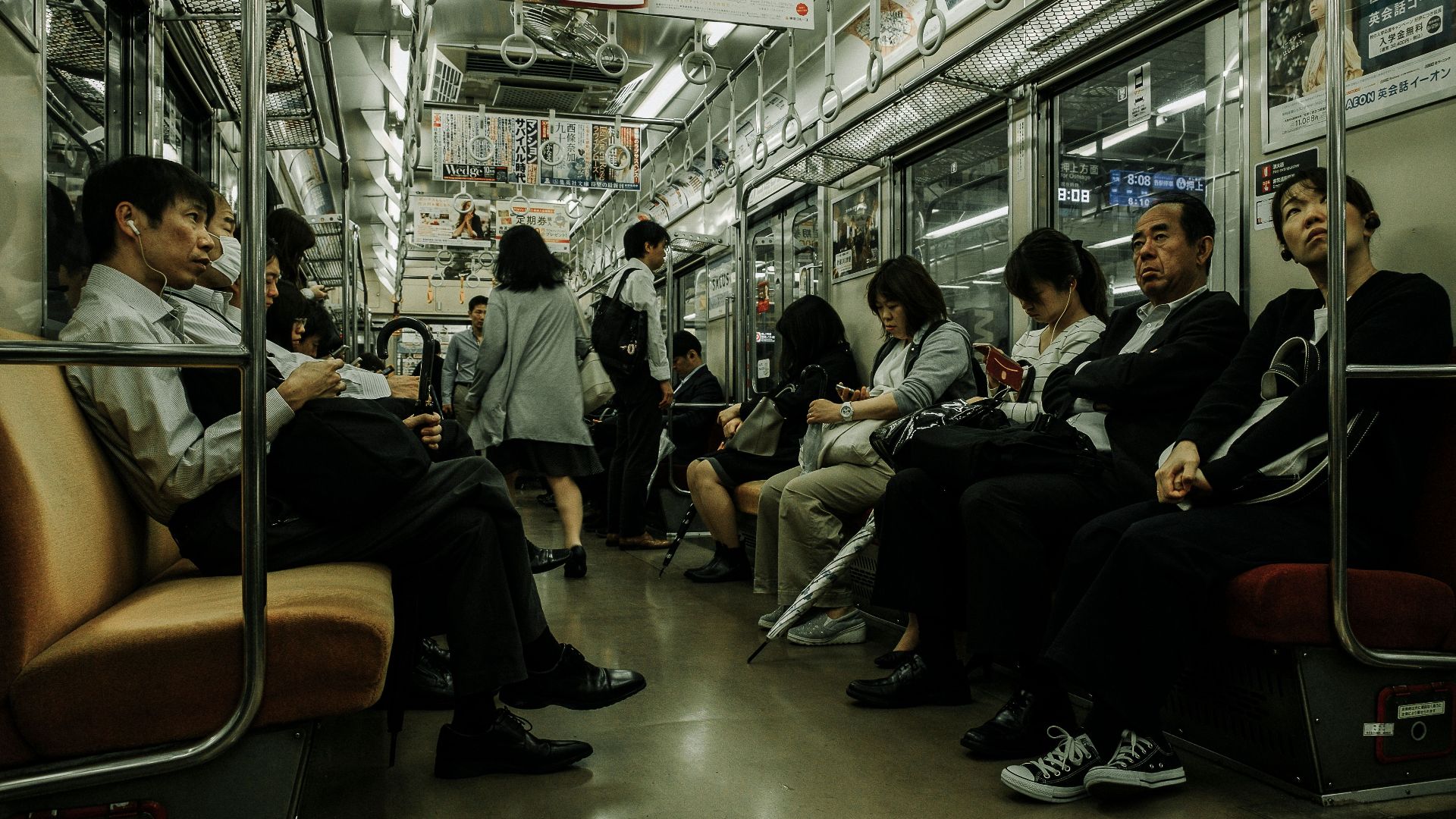 Passengers seated and standing in a busy subway train, showcasing daily public transportation.