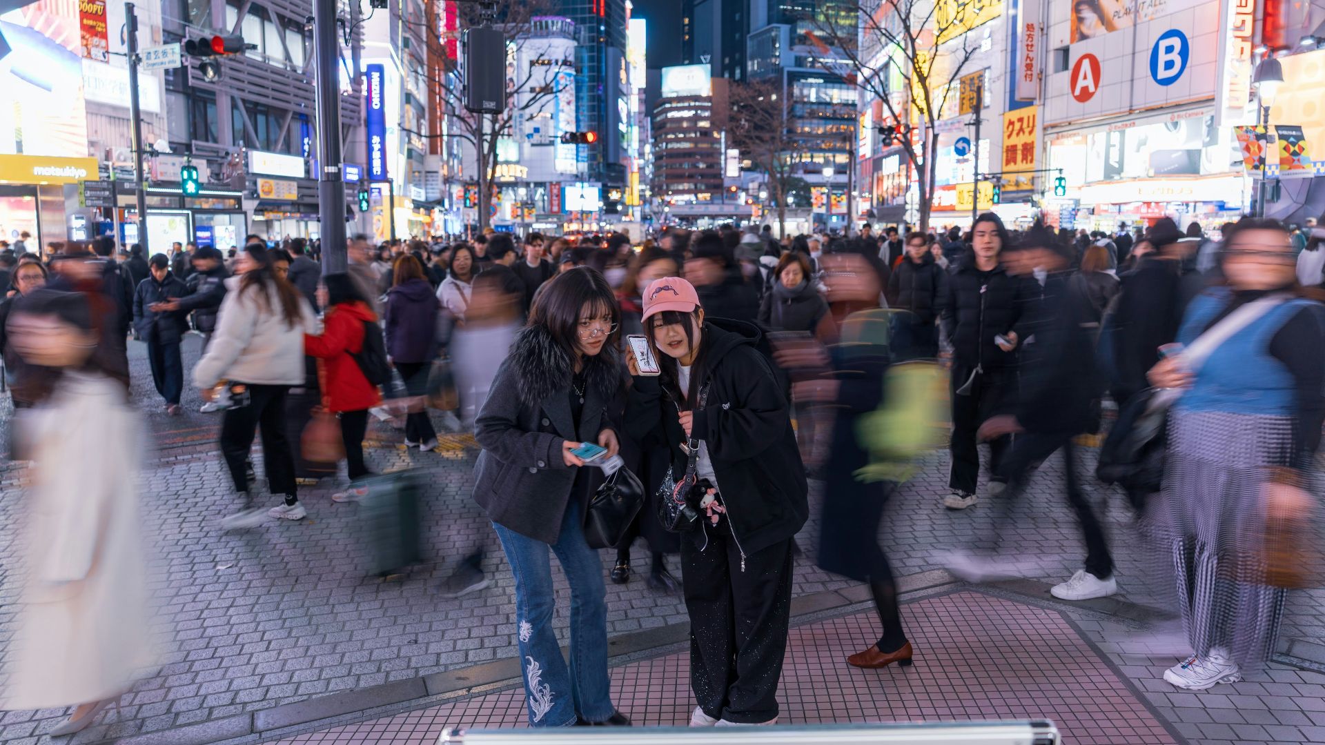 Crowded city street at night with vibrant neon lights.