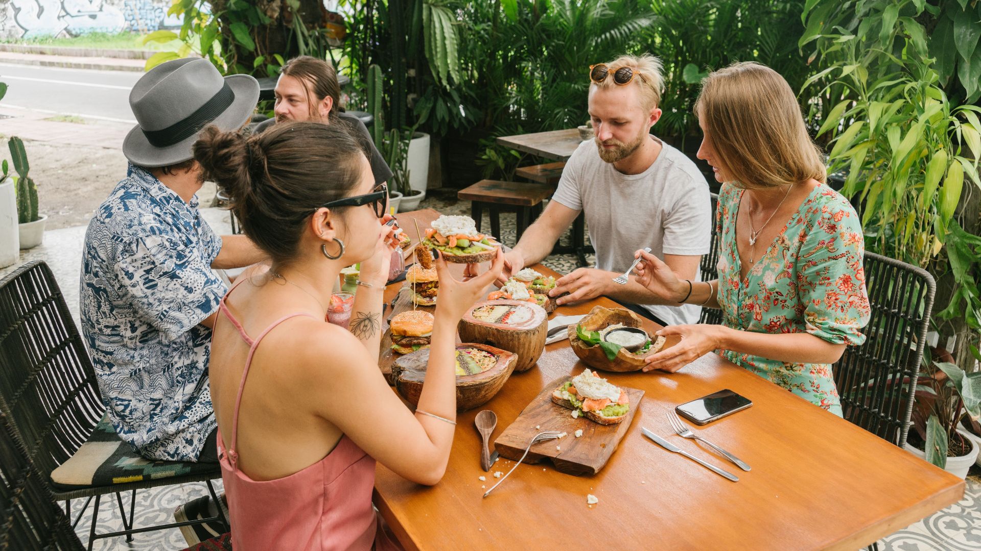 Group of friends dining on an outdoor patio, enjoying a relaxed brunch in a lush setting.