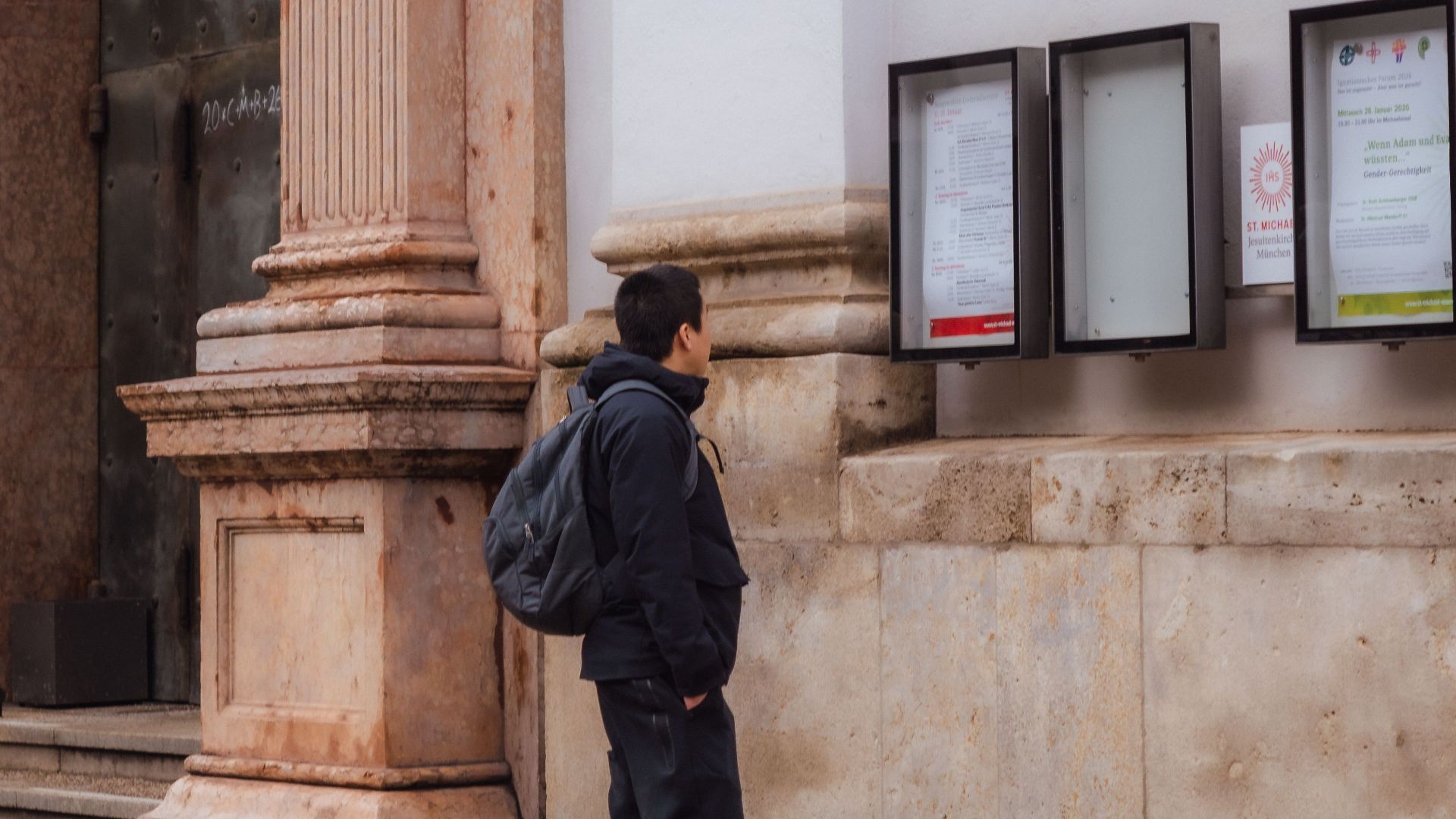 A man reads a notice board outside a historic church in Munich, Germany.