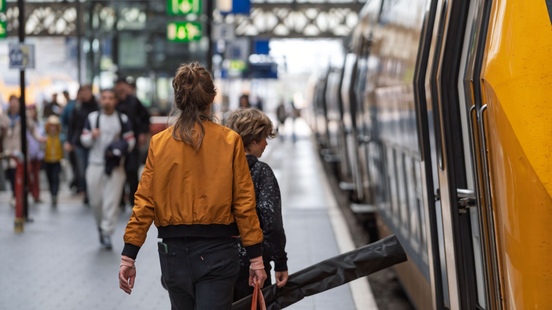 A woman and child boarding a train at a bustling station, capturing a moment of travel.