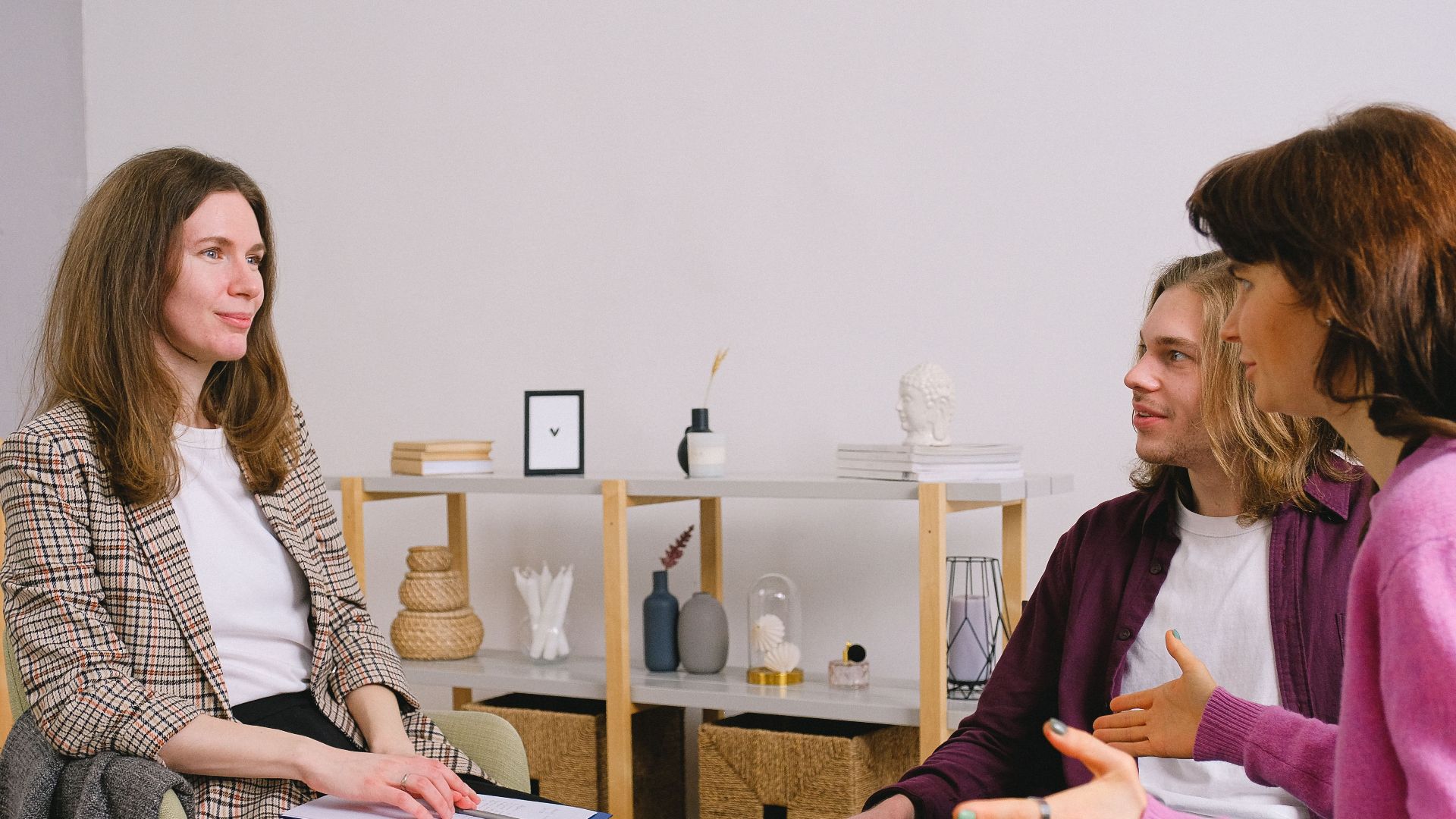 Young adults discuss with a counselor during an indoor therapy session.