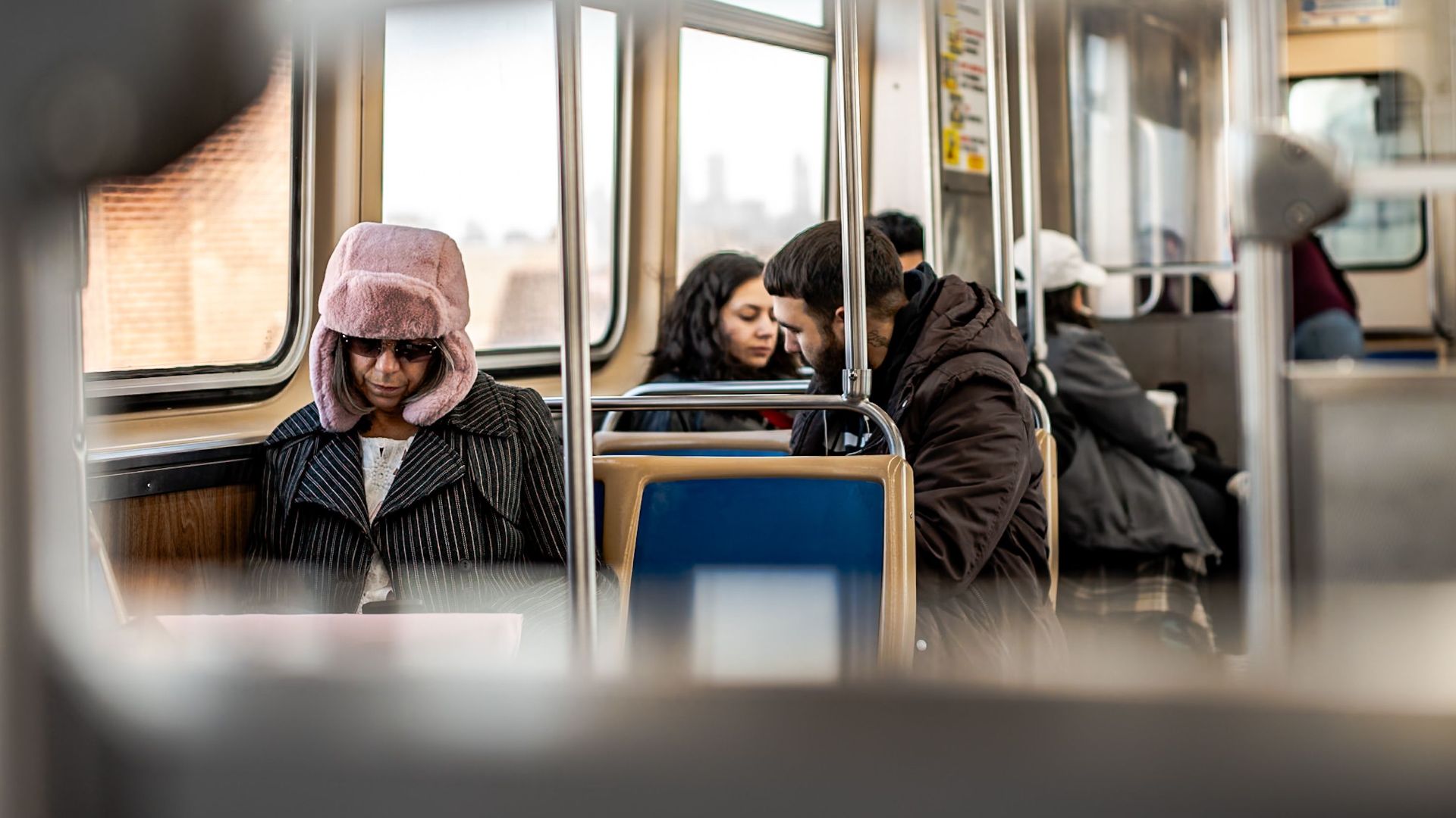 Passengers wearing winter coats and hats on a train during a city commute.
