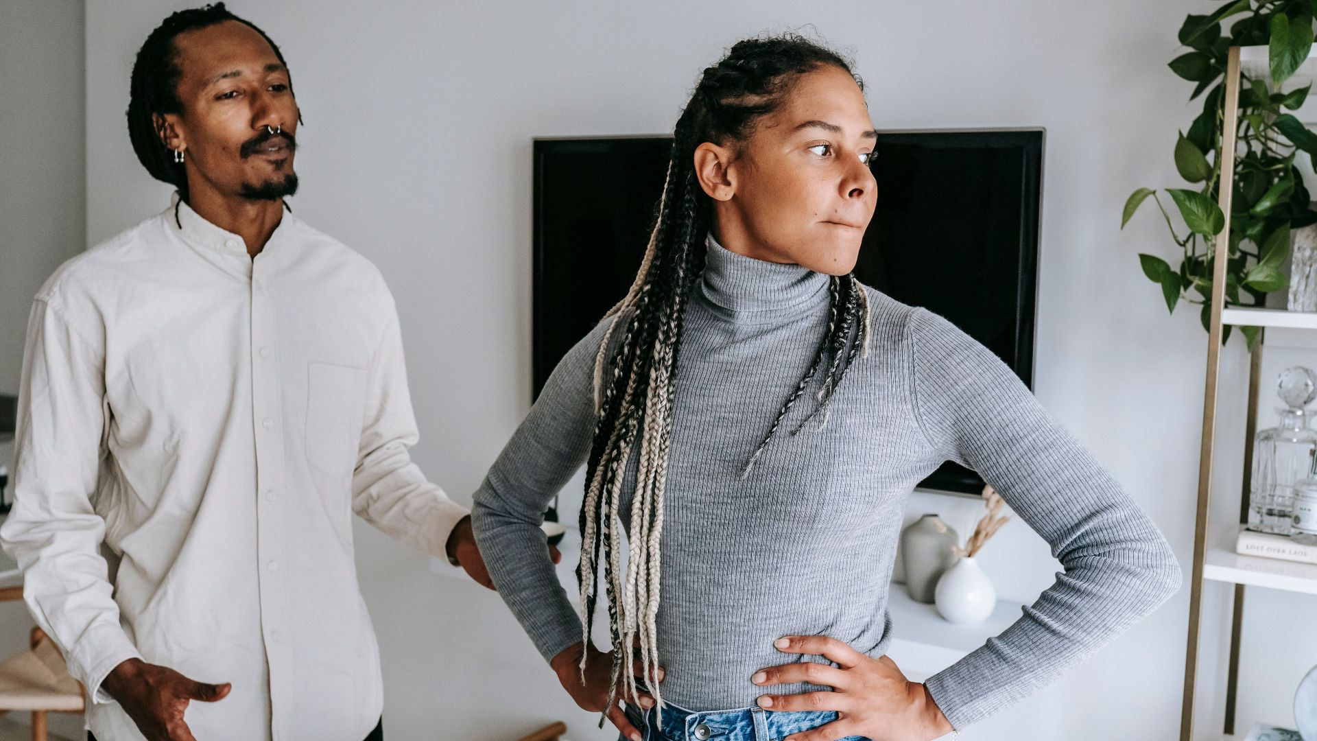 Unhappy African American couple quarreling while spending time together in light modern apartment