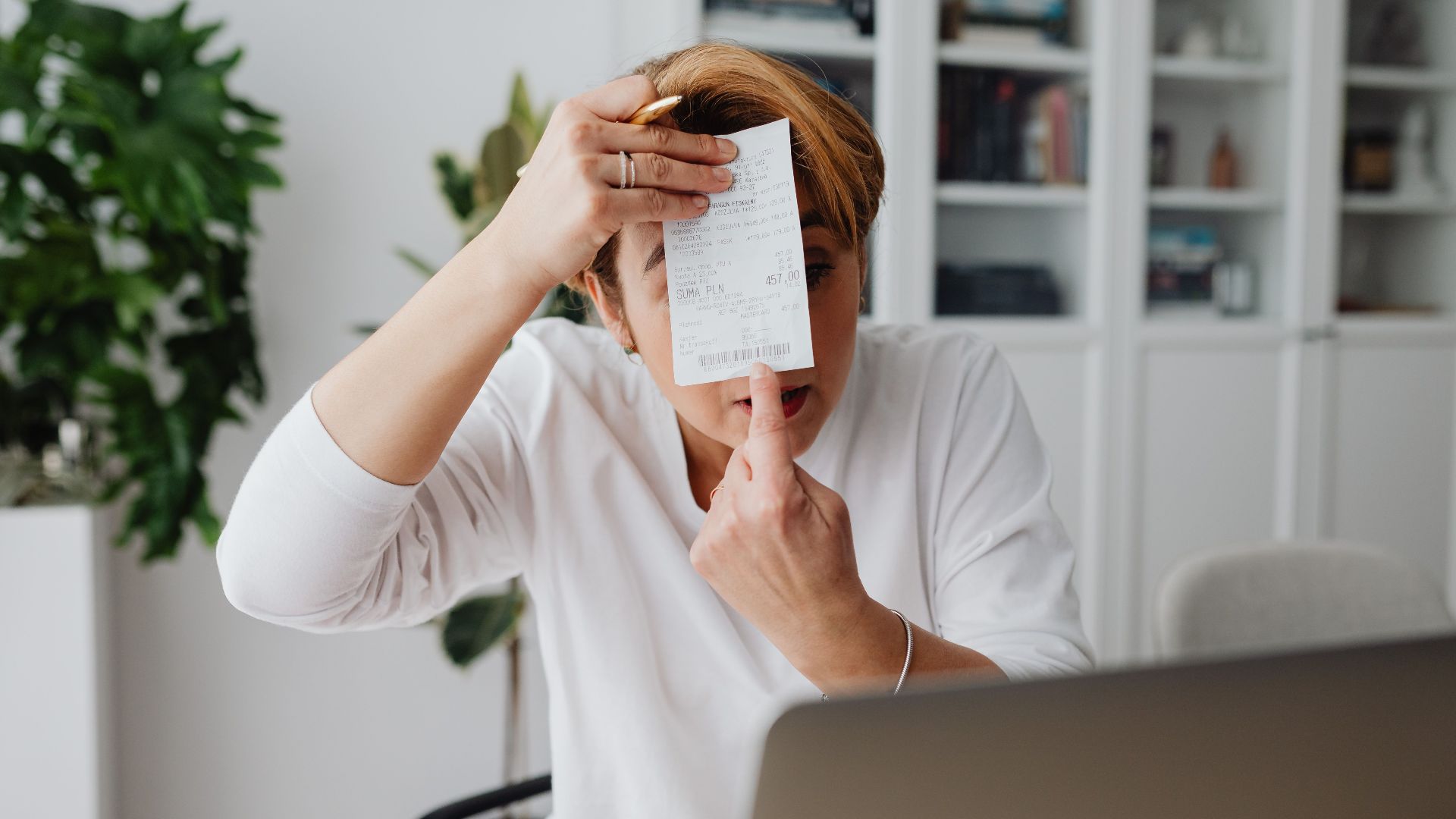 Businesswoman showing a receipt during a home office work session, highlighting technology integration.