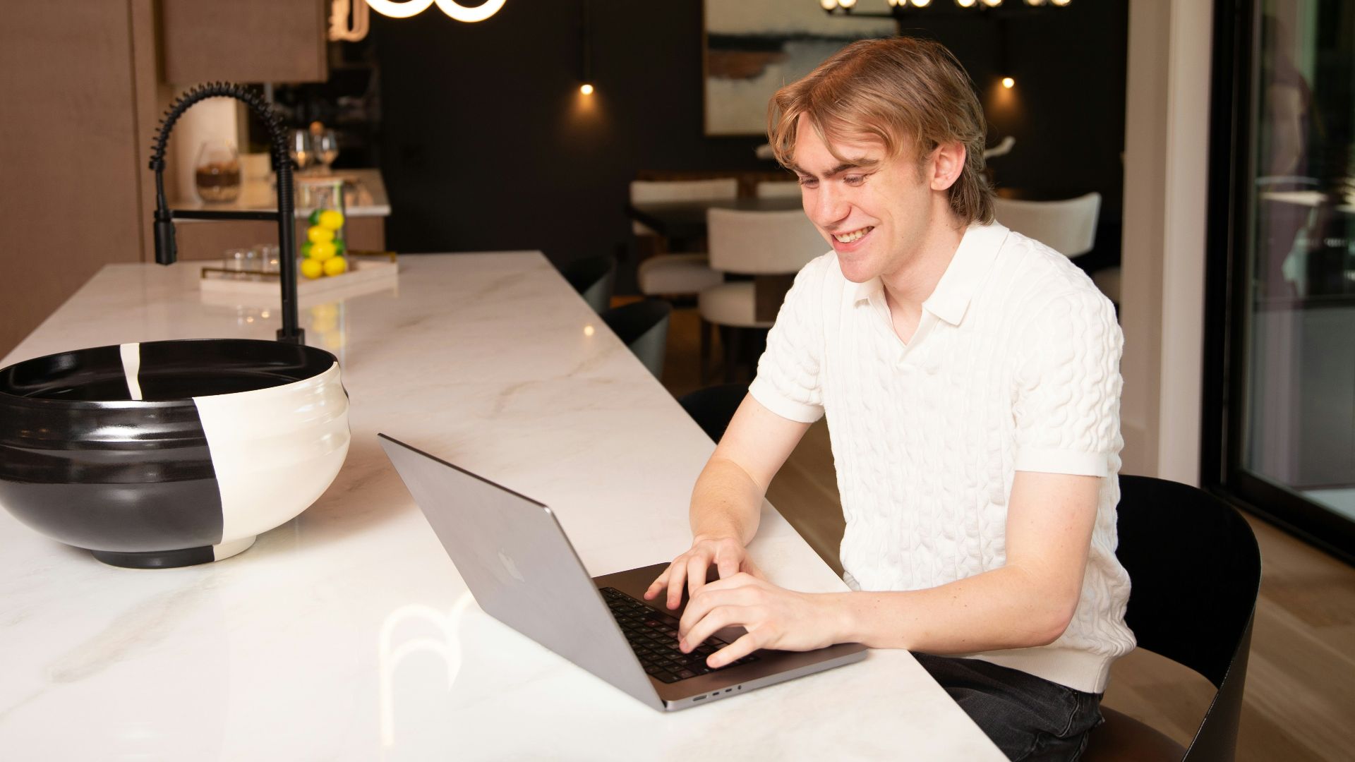 A man works on a laptop in a modern kitchen.