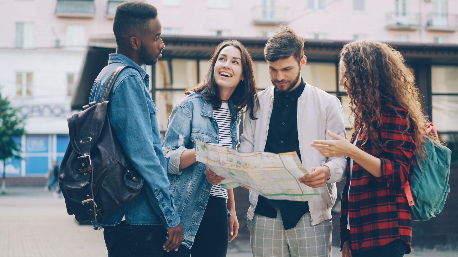 Four young friends reading a map outdoors, planning their city adventure.