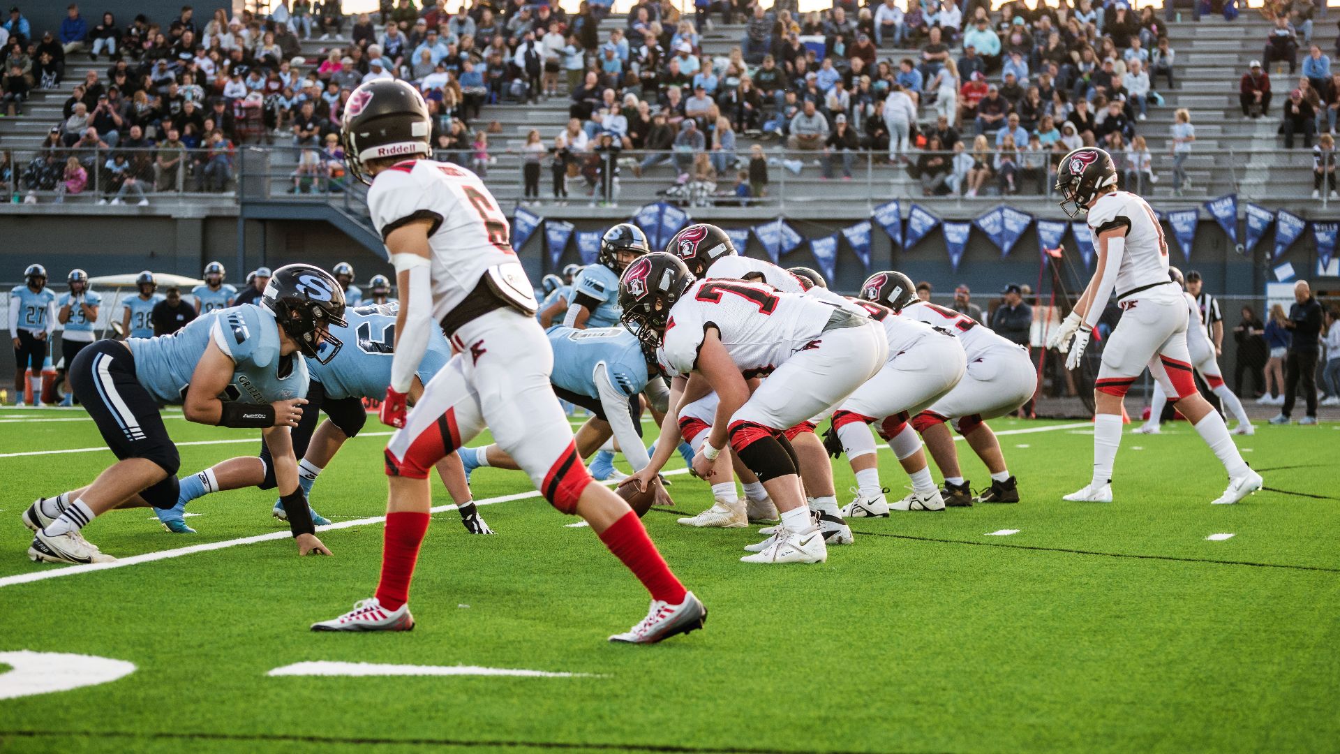 Players in action during a competitive high school football game at an outdoor stadium.