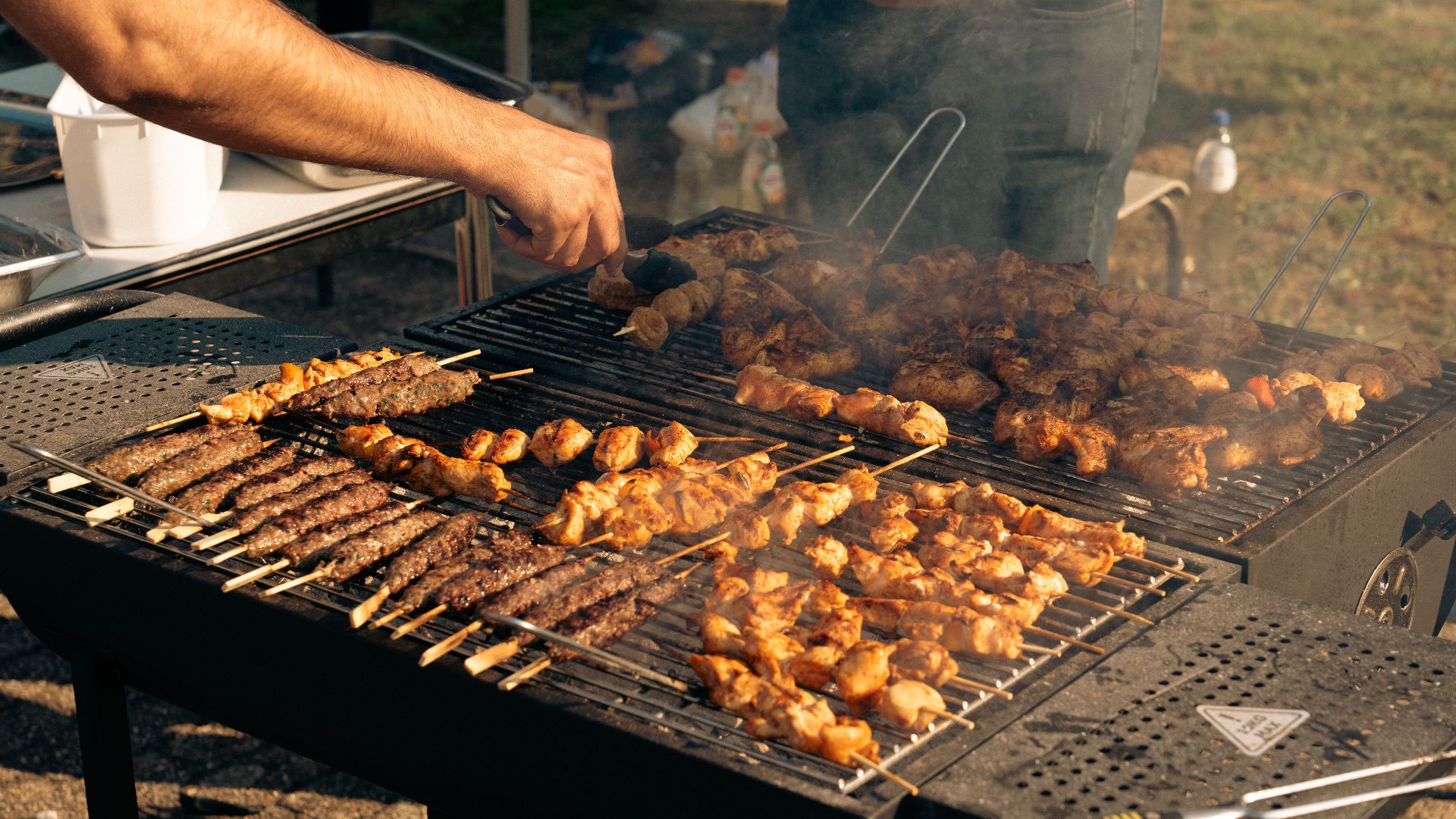 A variety of skewered meats being grilled on an outdoor barbecue. Perfect for summer gatherings.