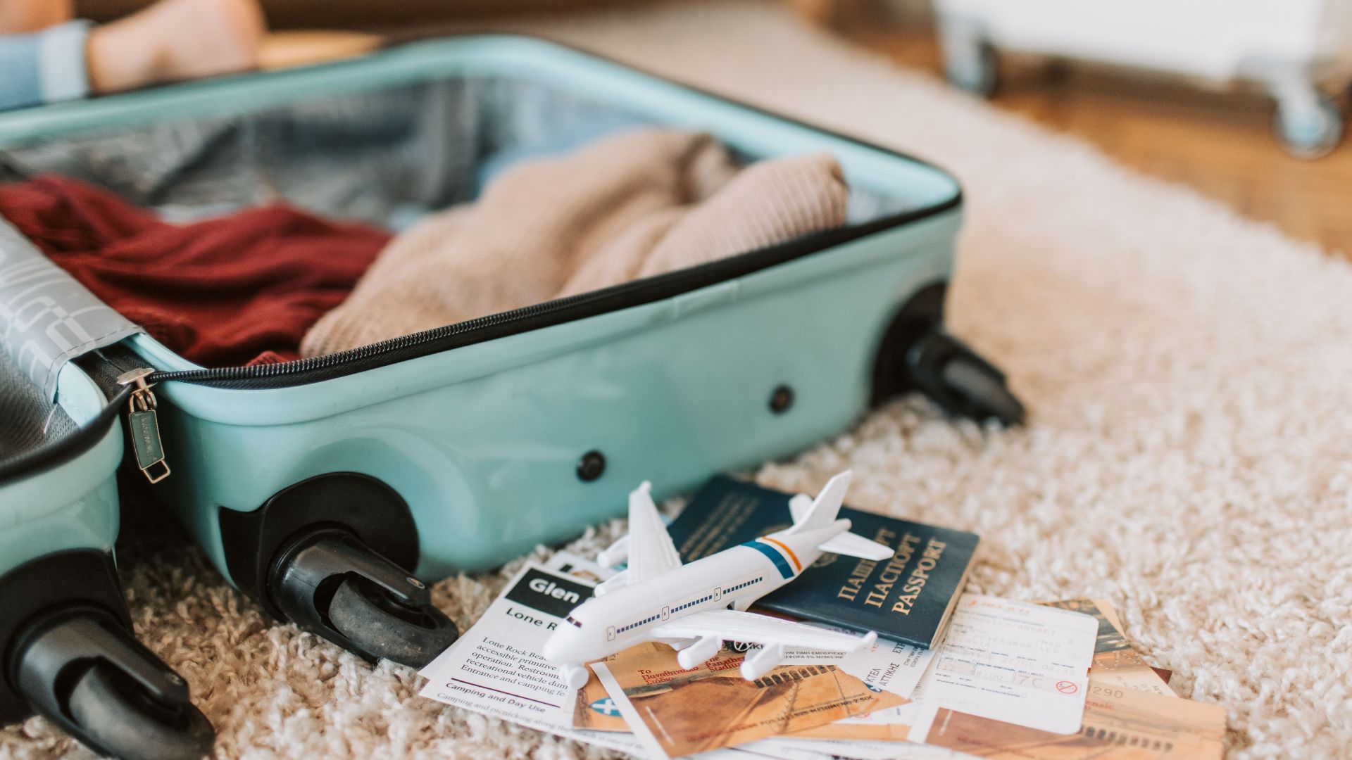 Close-up of an open suitcase with travel essentials like passport and tickets, ready for a journey.
