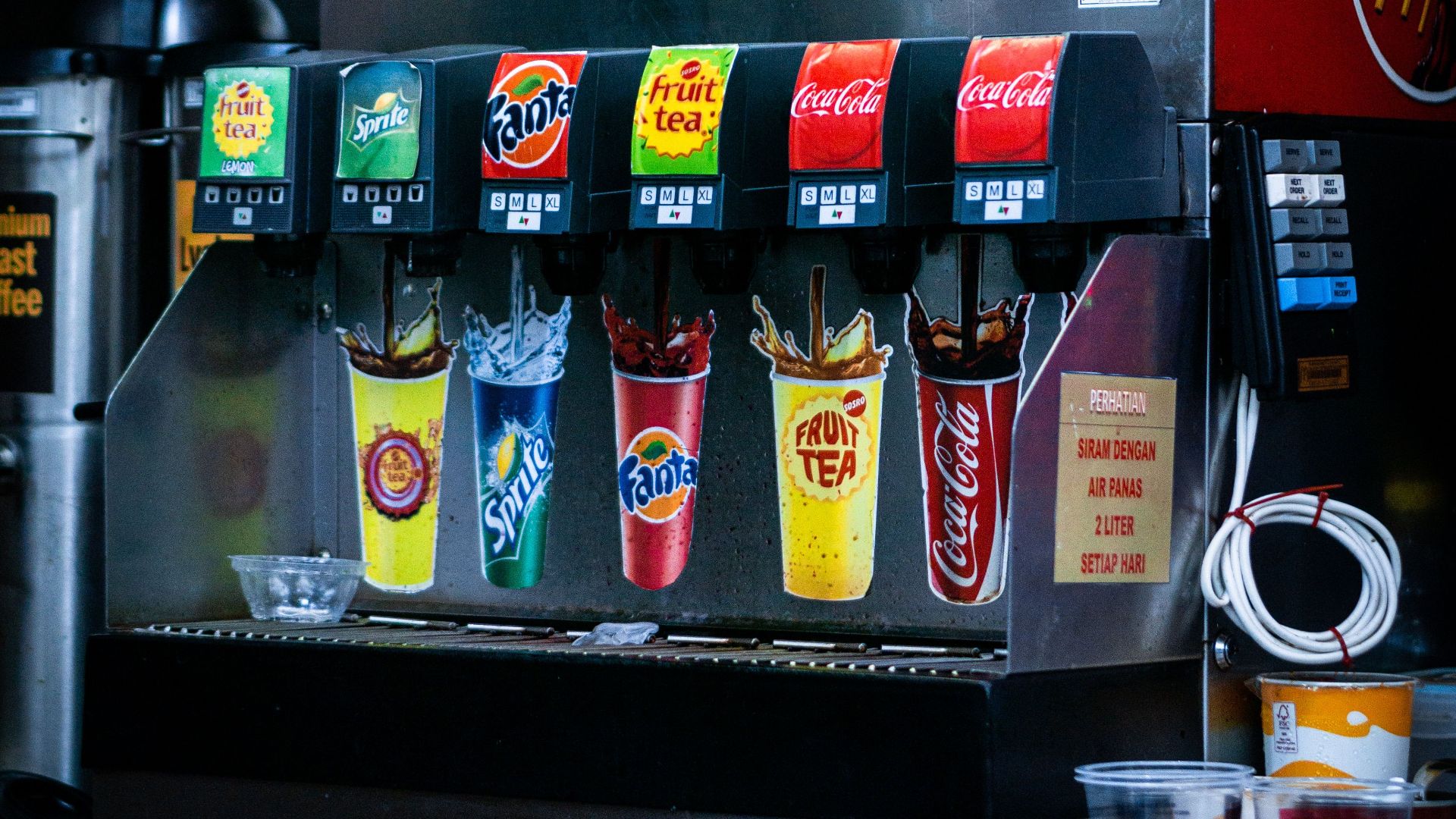 Soft drink dispenser with various soda options in fast food restaurant.