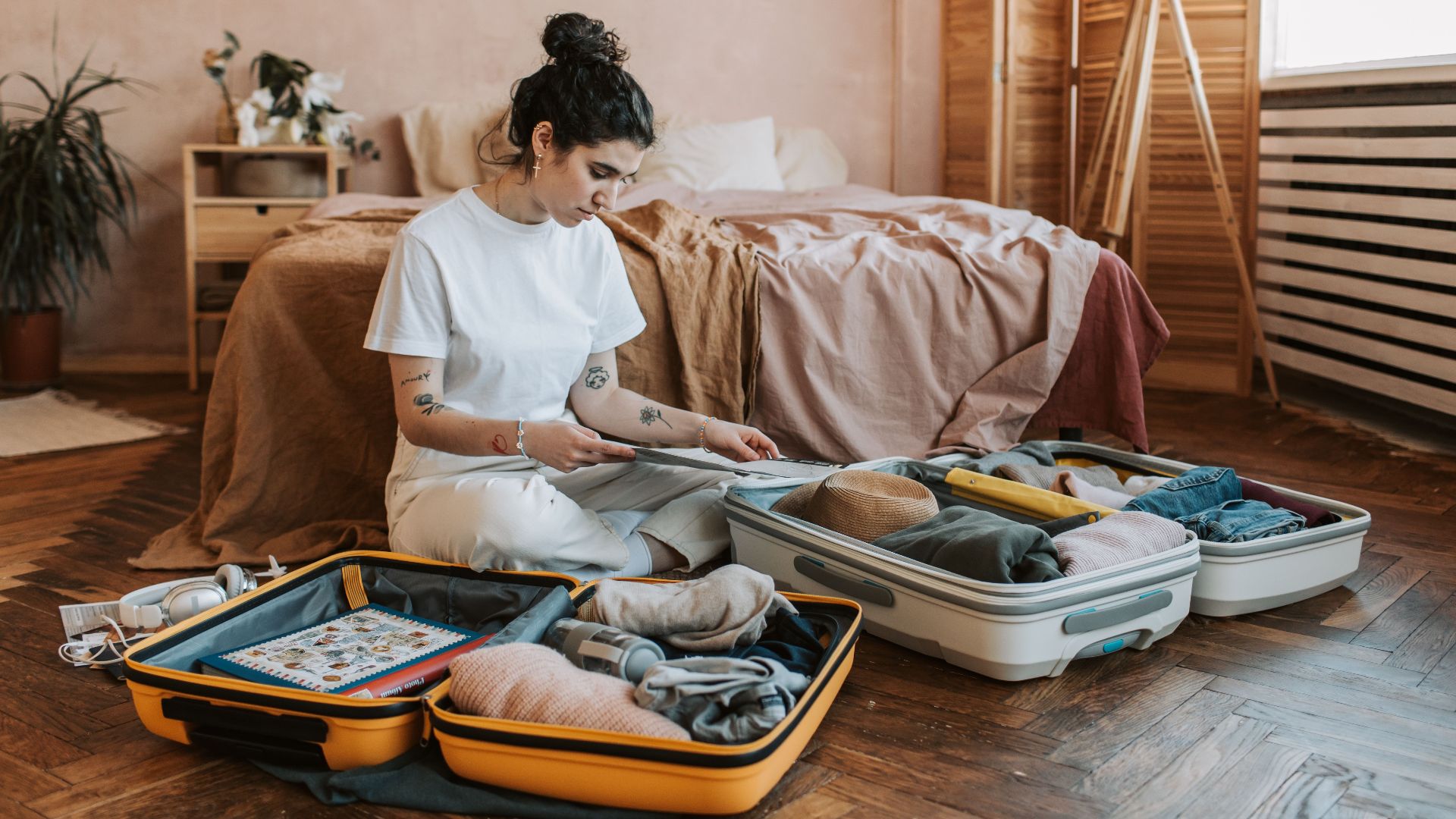 A woman organizes luggage in a stylish bedroom, carrying wanderlust vibes.