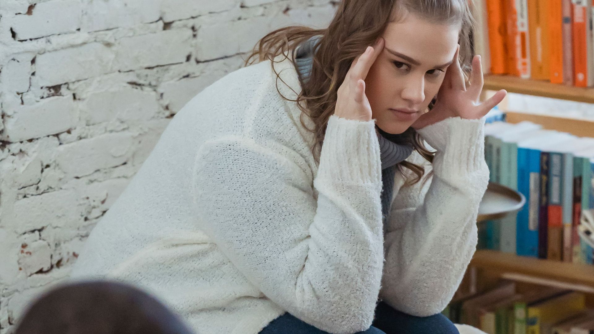 Unhappy wife looking at husband with discontent after quarrel while man sitting and browsing laptop