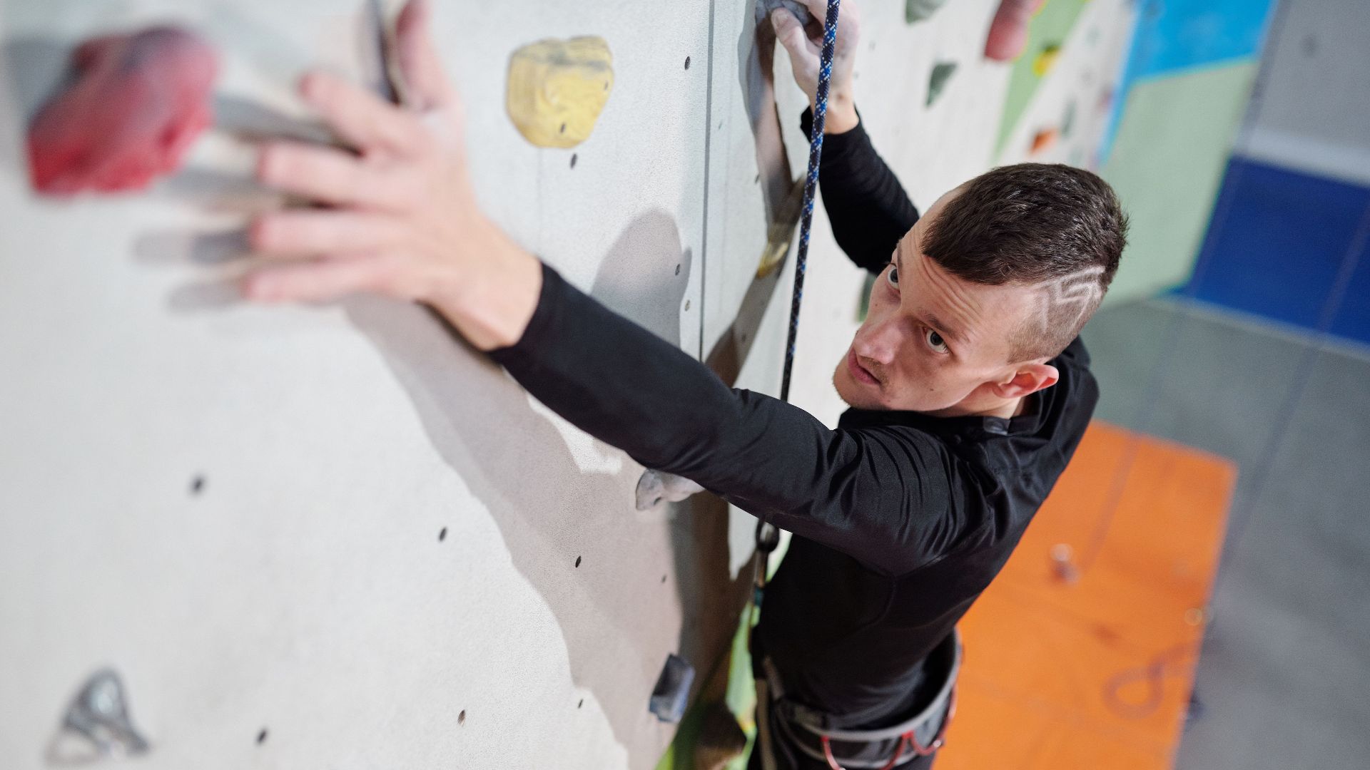 An inspiring image of an amputee man climbing an indoor wall showcasing strength and determination.
