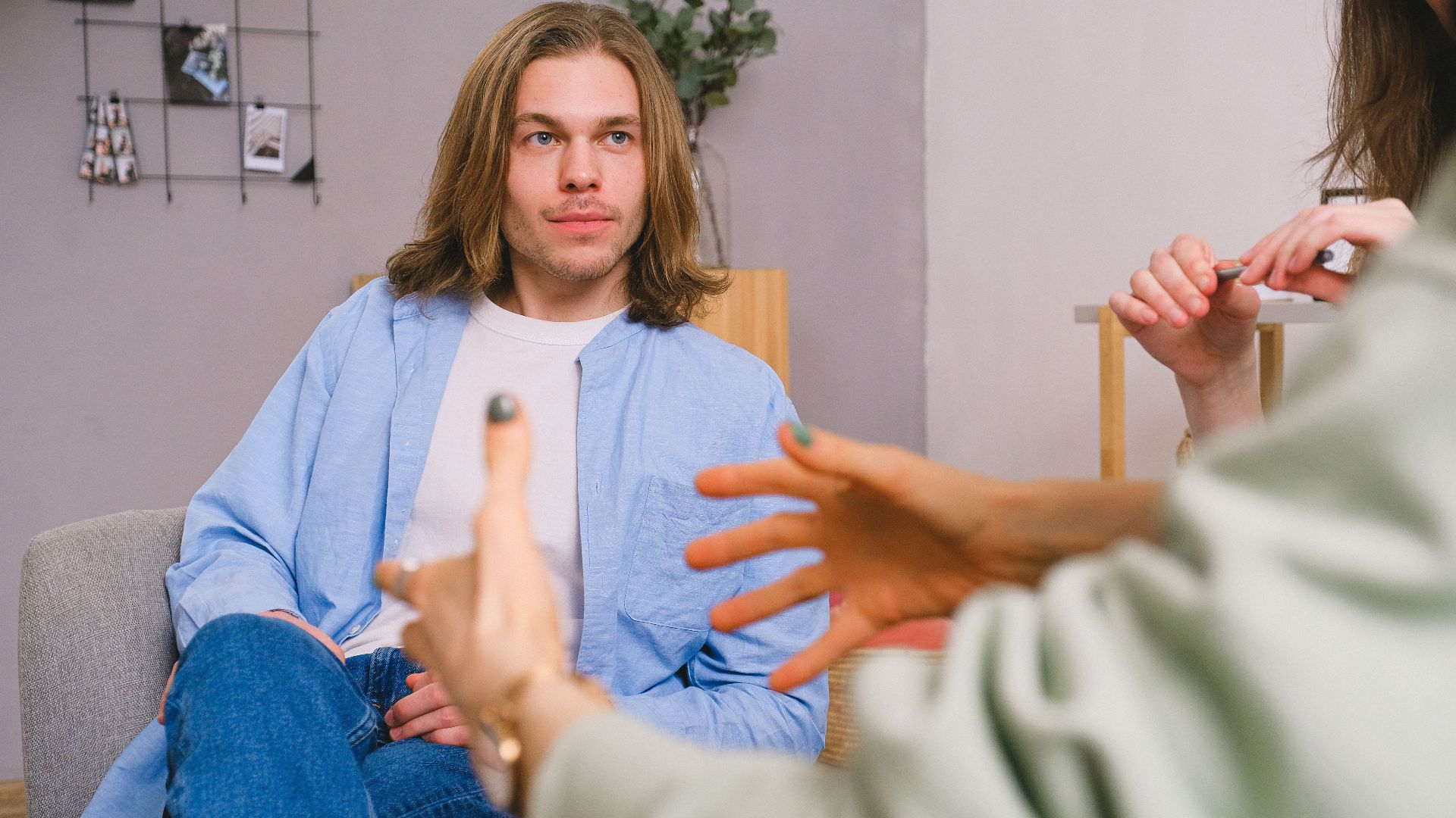 Unrecognizable therapist talking to male patient and anonymous partner during psychotherapy session in light office