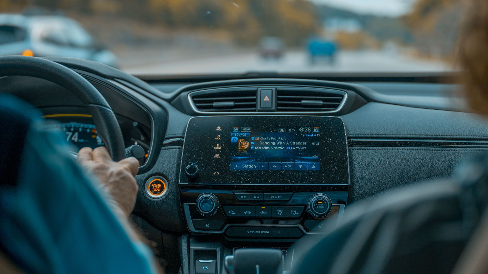View from inside a car focusing on the dashboard, steering wheel, and road ahead.