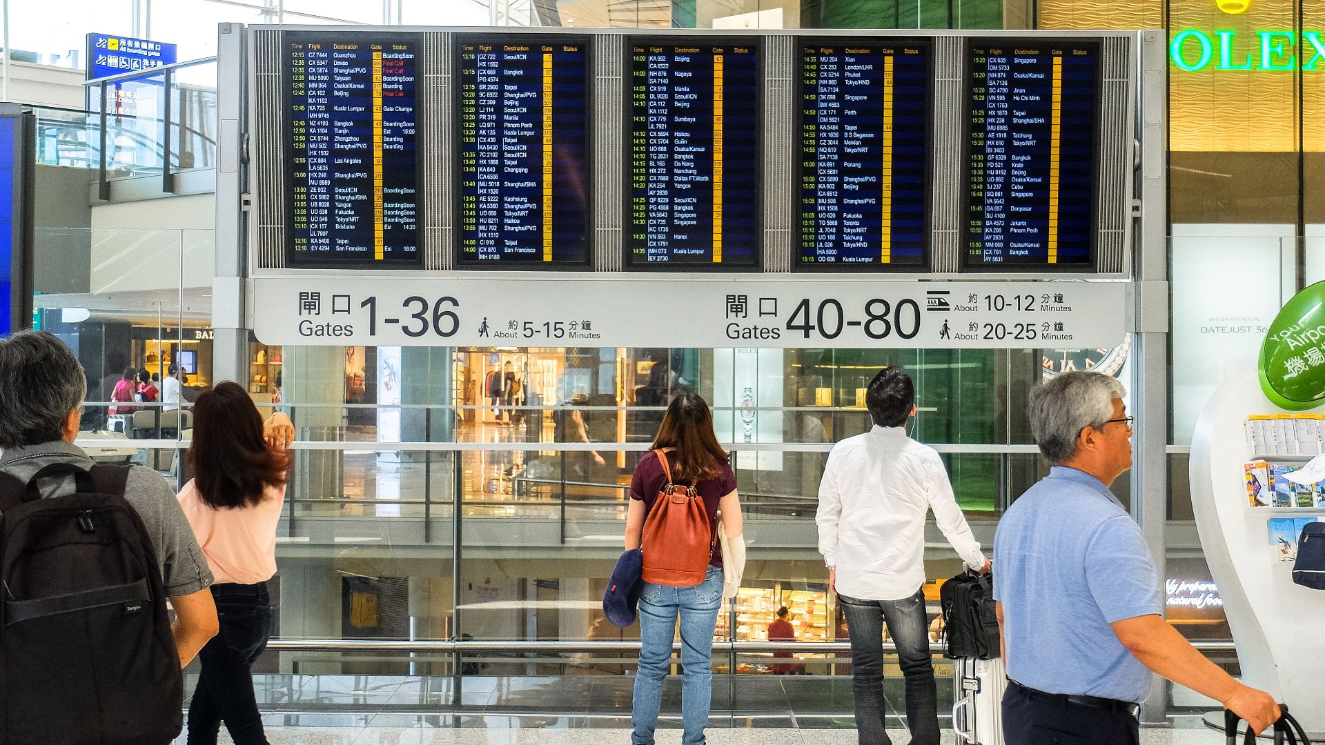Passengers checking the departure board at Hong Kong International Airport terminal.