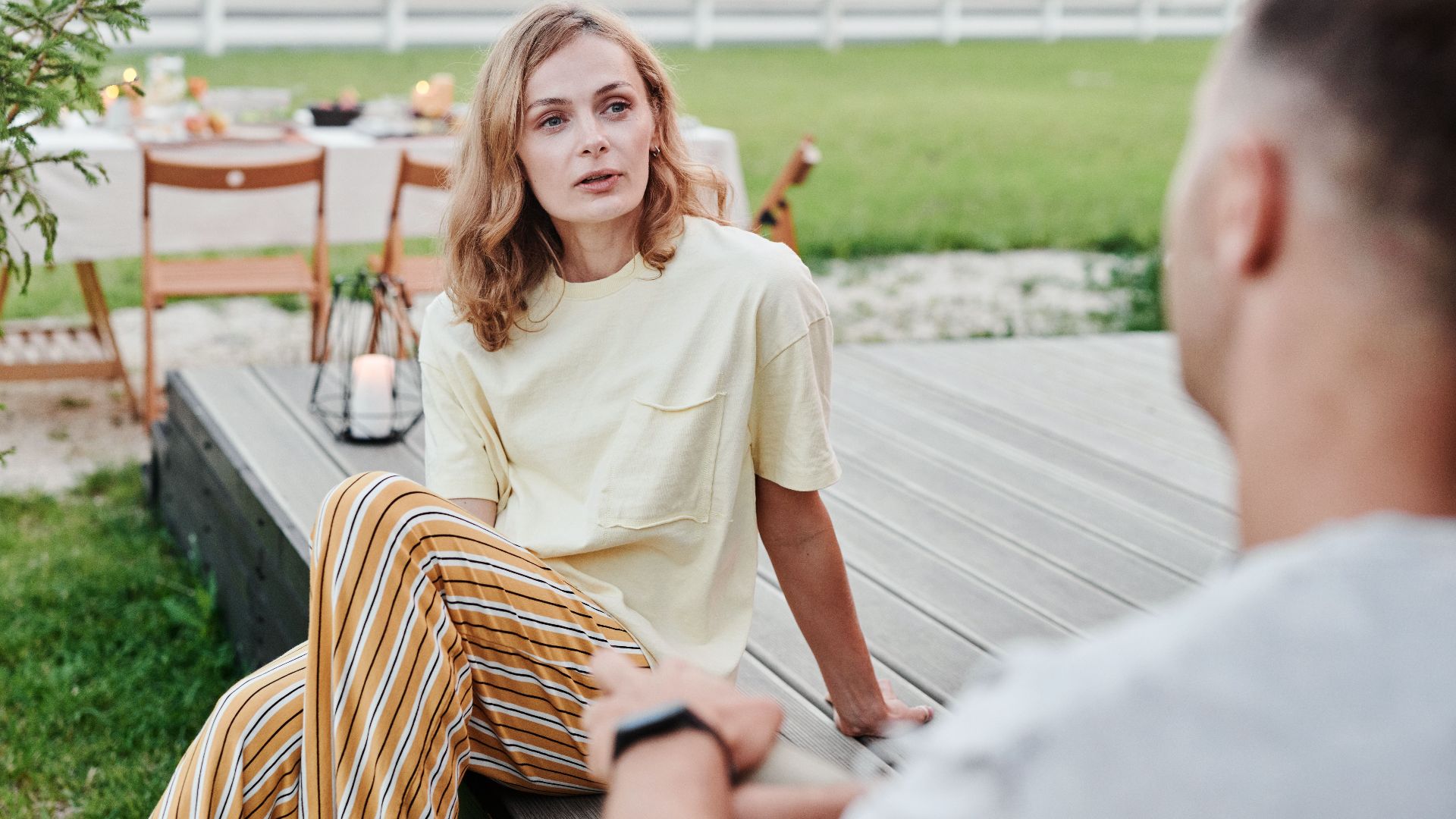 A couple engaged in a thoughtful conversation outdoors in a relaxed garden setting.