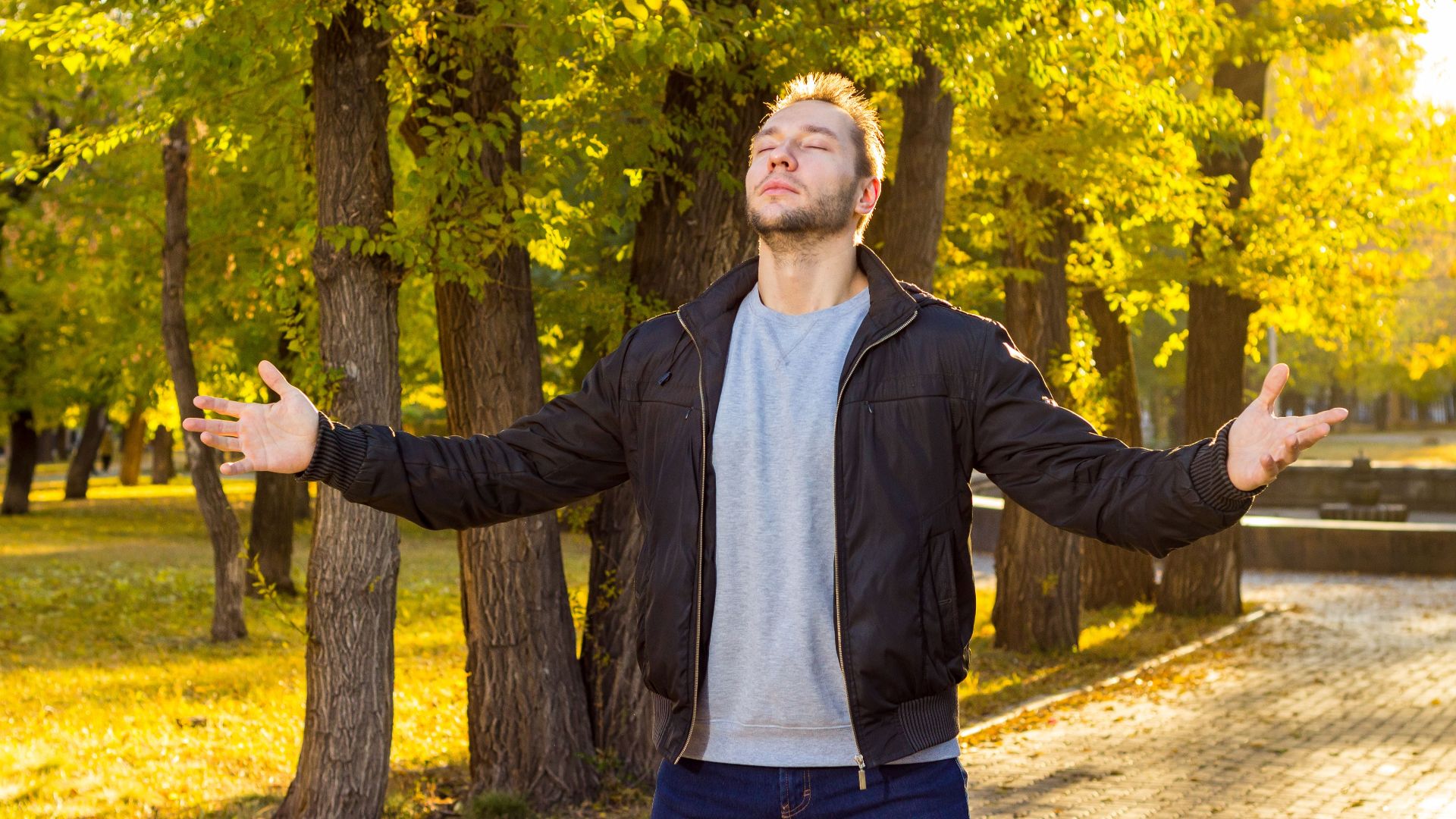 Caucasian man with eyes closed embracing nature in an autumn park.