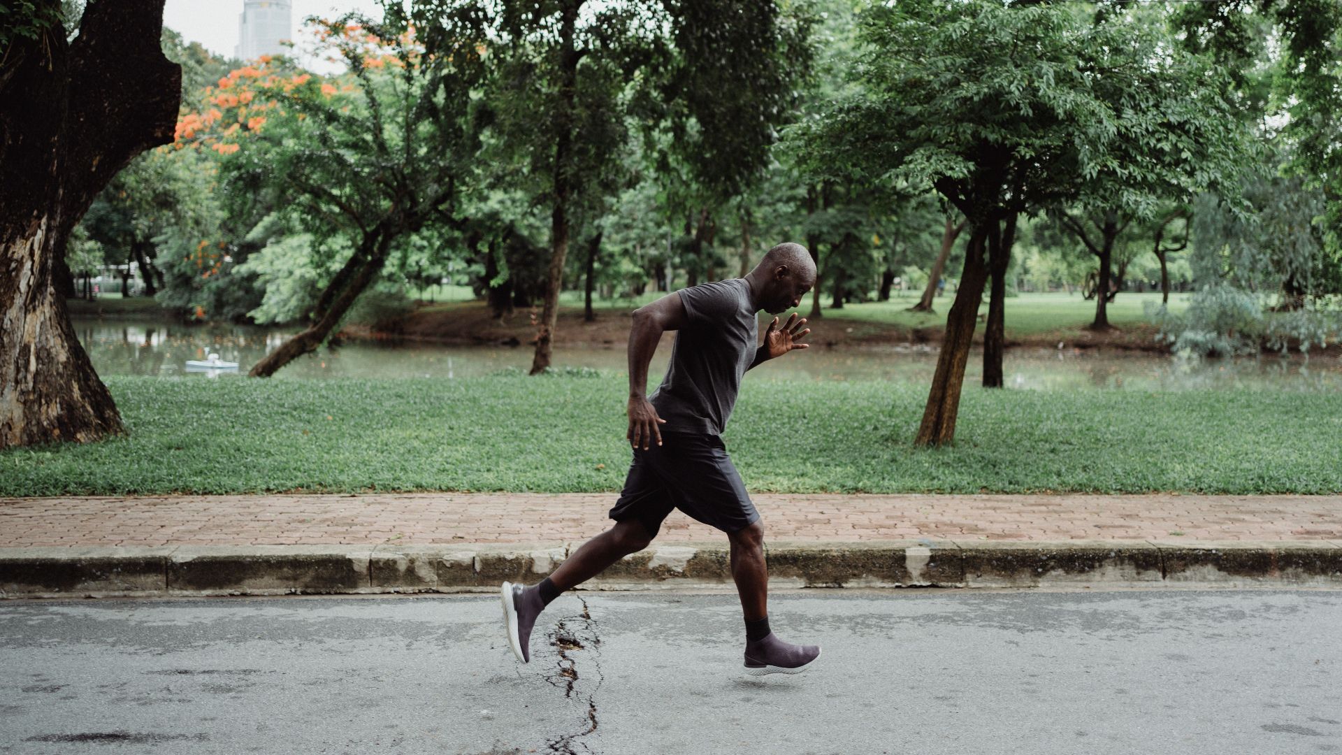 A man jogging on a path in a vibrant green park, showcasing a healthy lifestyle.