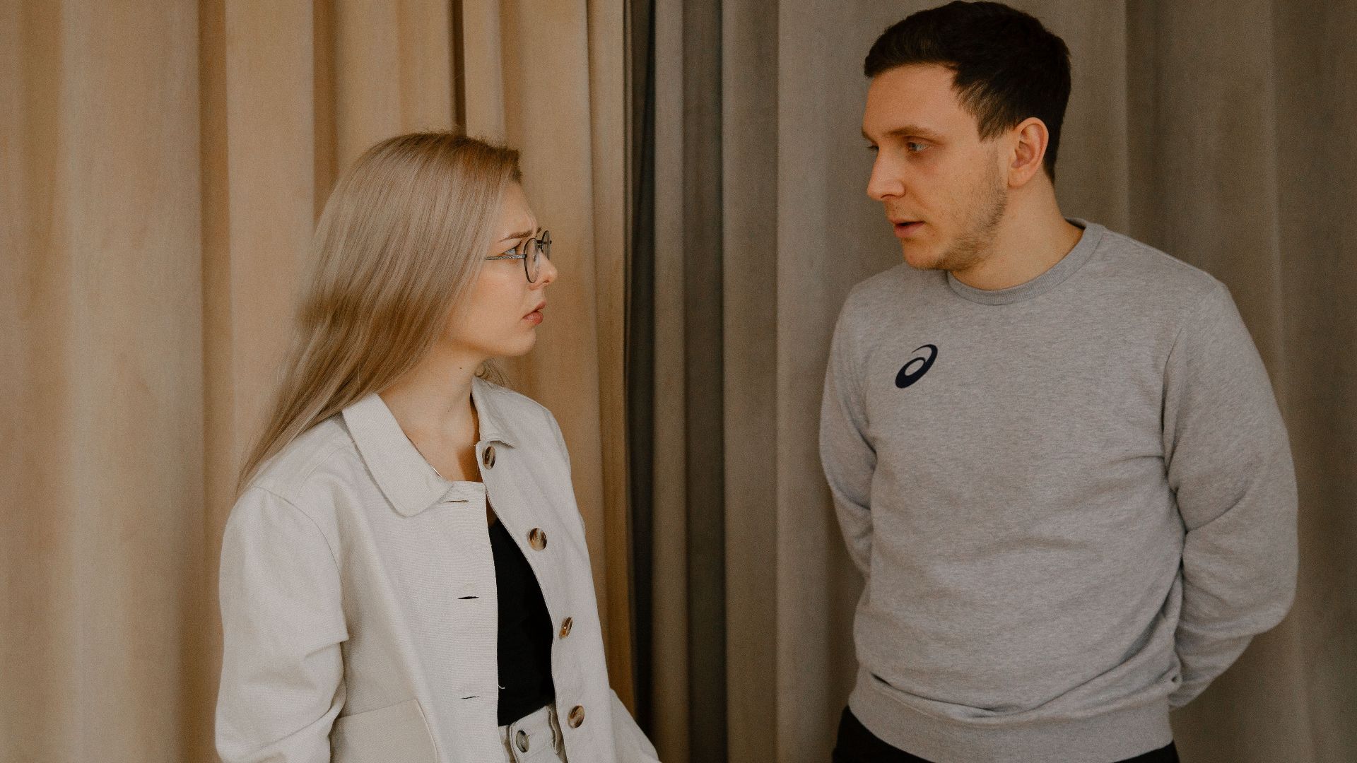 Man and woman having a serious conversation indoors, focused expressions.