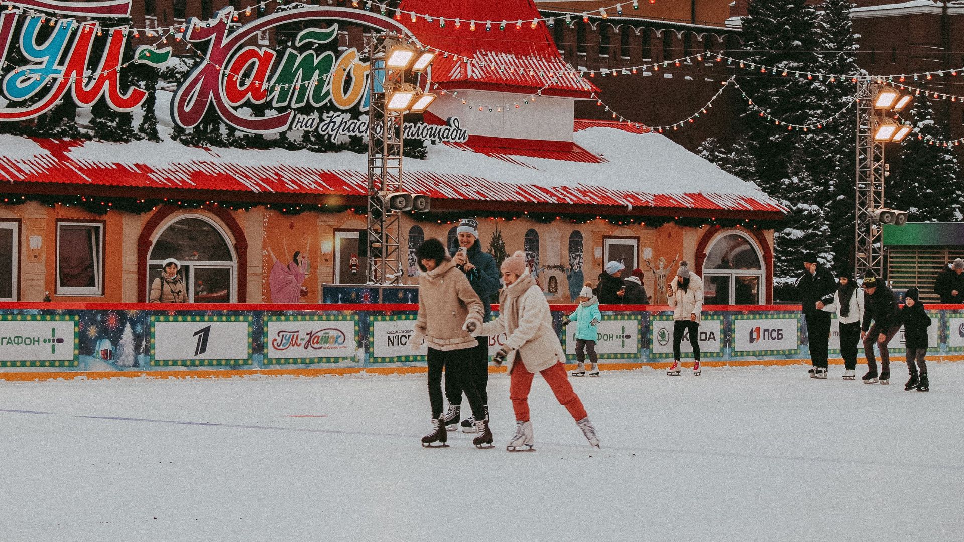 A lively scene at a decorated ice skating rink with people enjoying winter activities in a festive atmosphere.