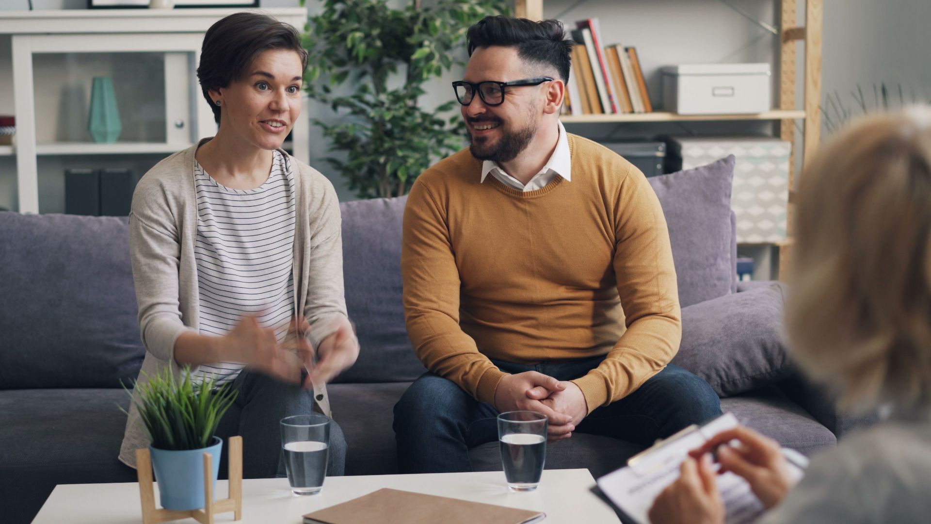 A couple discussing with a therapist during a counseling session indoors.