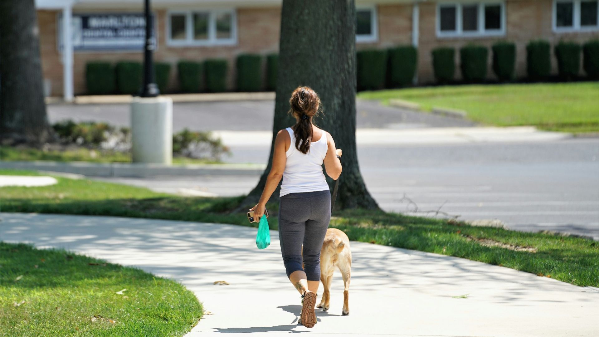 woman in gray tank top and blue denim shorts running on gray concrete road during daytime