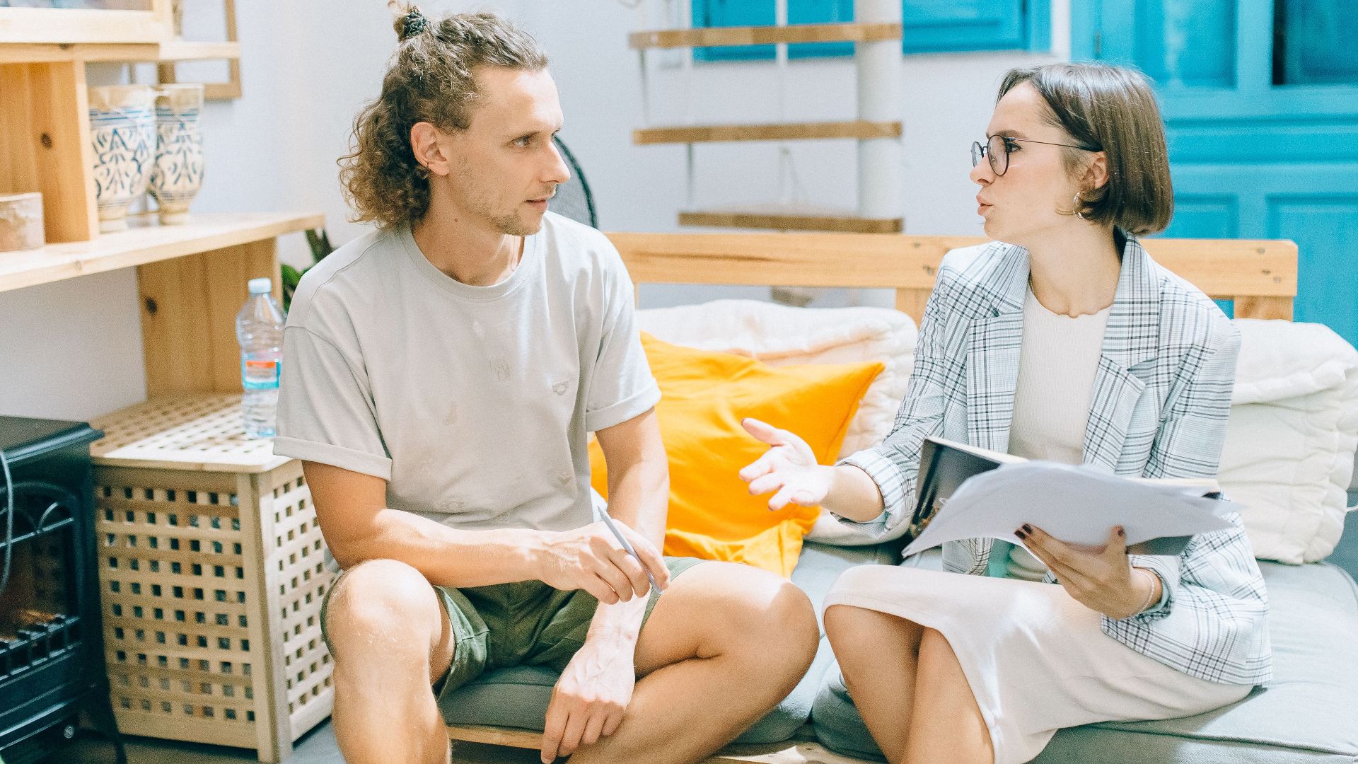 A man and woman discussing work in a stylish, bright living room setting.