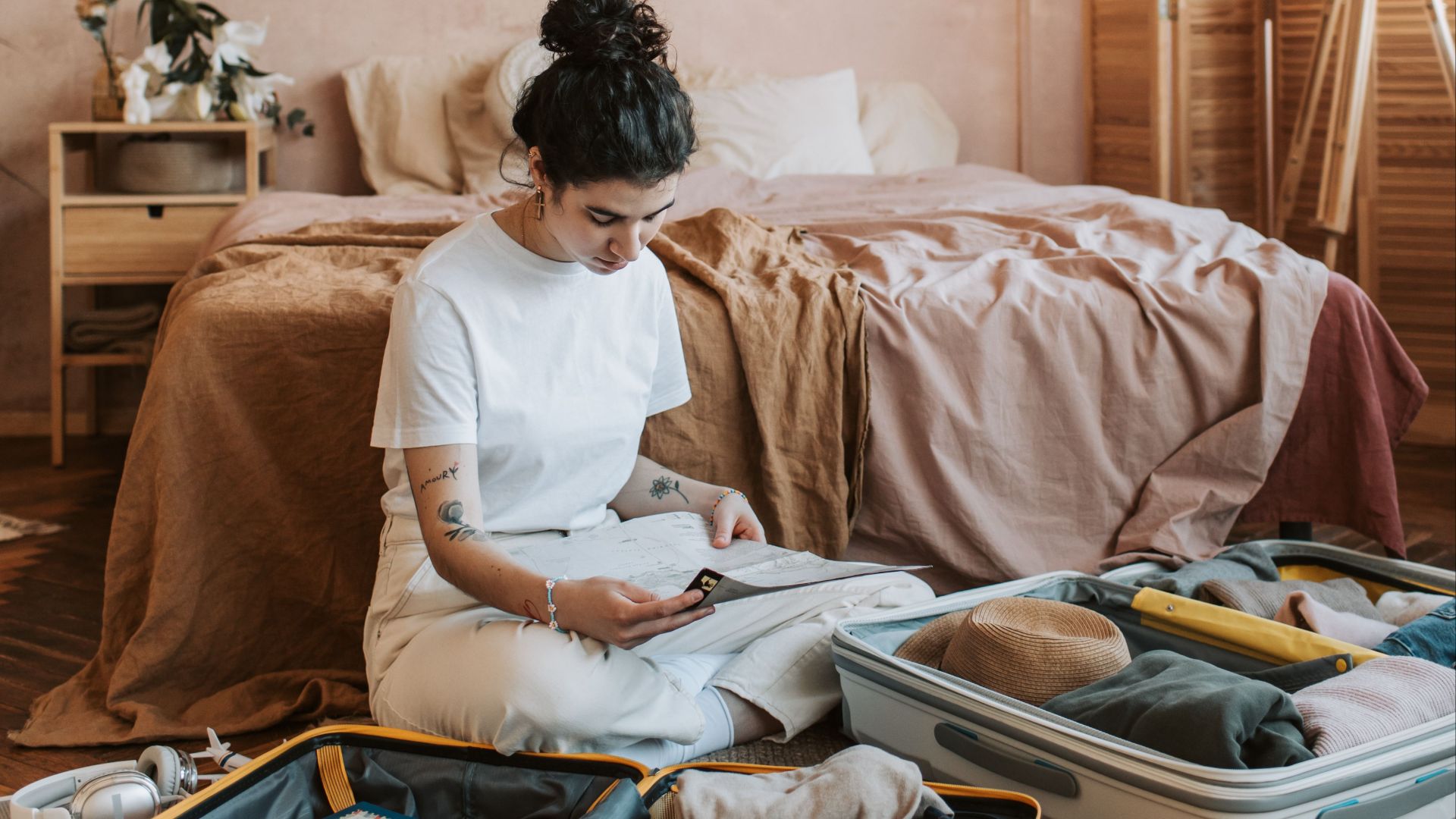 Woman organizing clothes in suitcase on bedroom floor, creating a relaxed travel vibe.