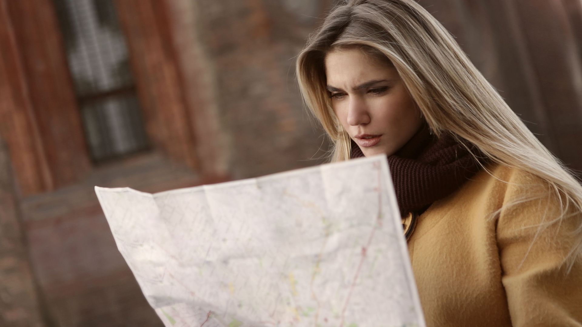 A woman intently reads a map outdoors, highlighting navigation and exploration.